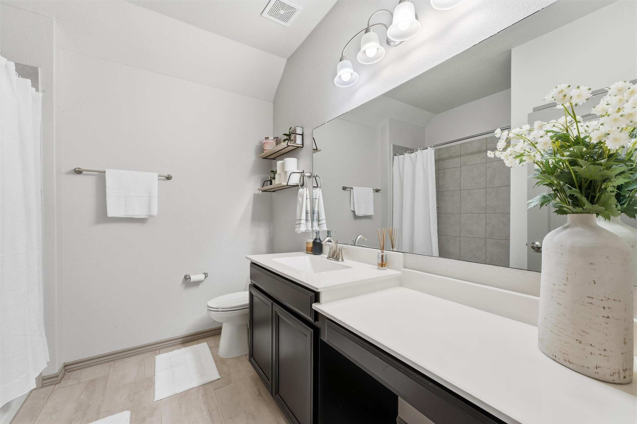 Well-appointed bathroom featuring a spacious vanity, contemporary fixtures, generous counter space, and neutral finishes.