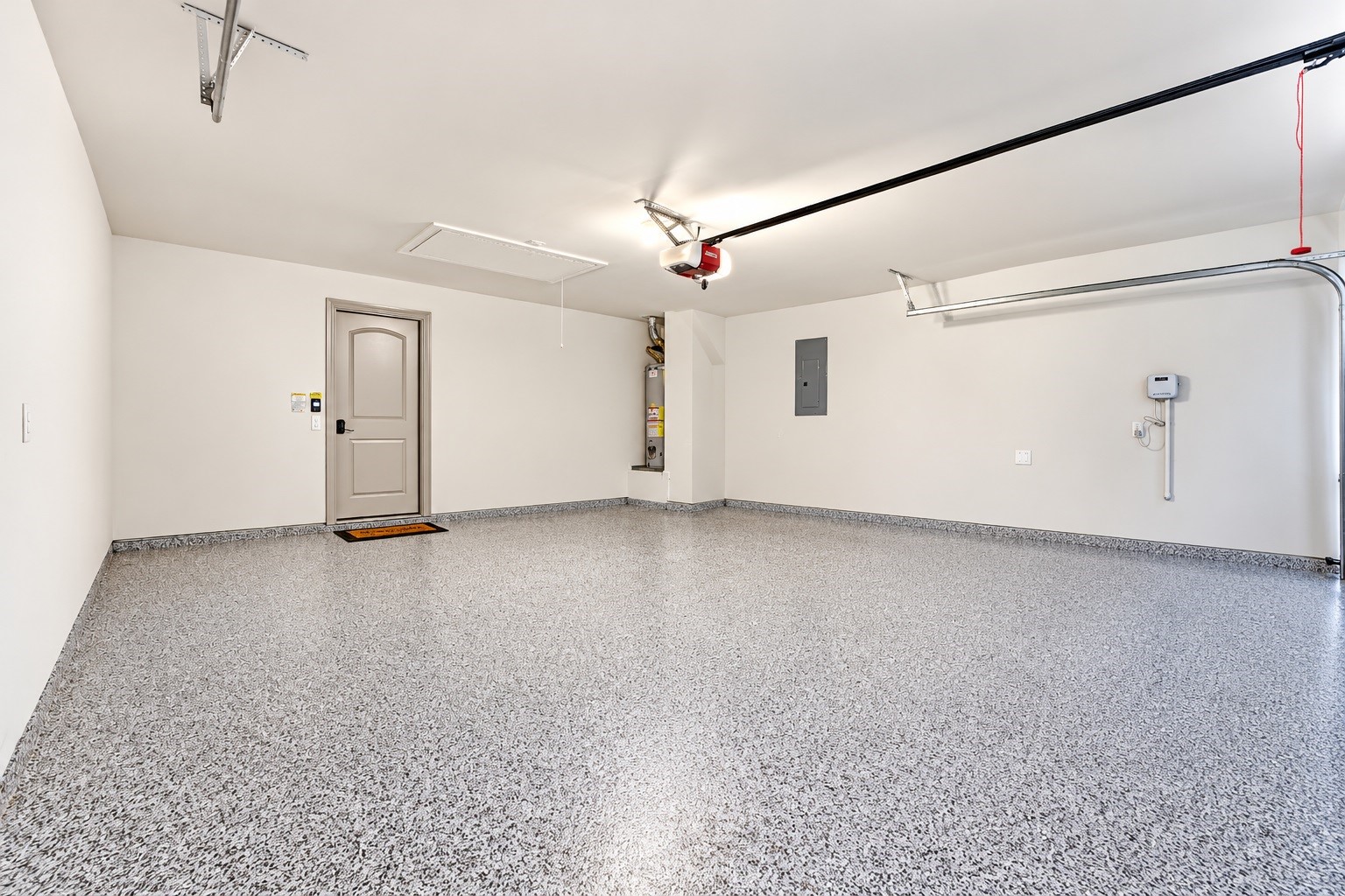 Spacious two-car garage featuring durable epoxy-coated flooring, a clean finished interior, and ample room for parking, storage, and organization.