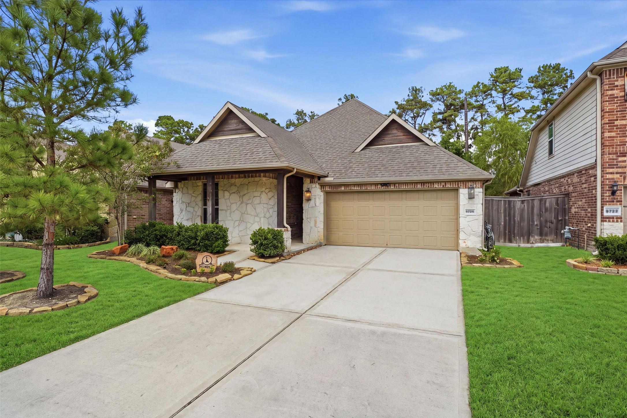 Beautiful single-story home featuring a stone-and-brick exterior, welcoming covered entry, manicured landscaping, and a two-car garage.