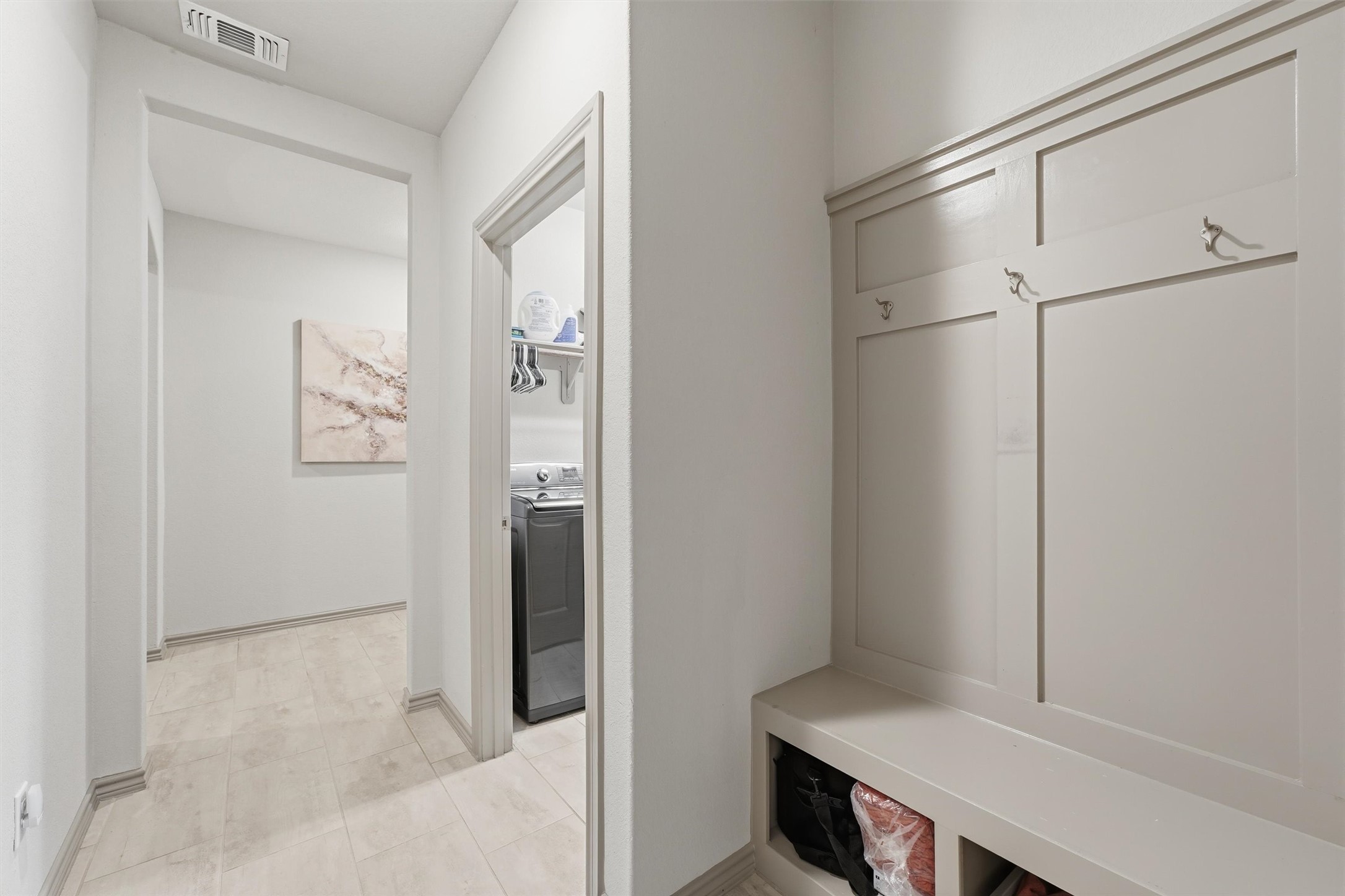 Convenient mudroom featuring custom built-in bench seating, coat hooks, and easy access to the laundry room.