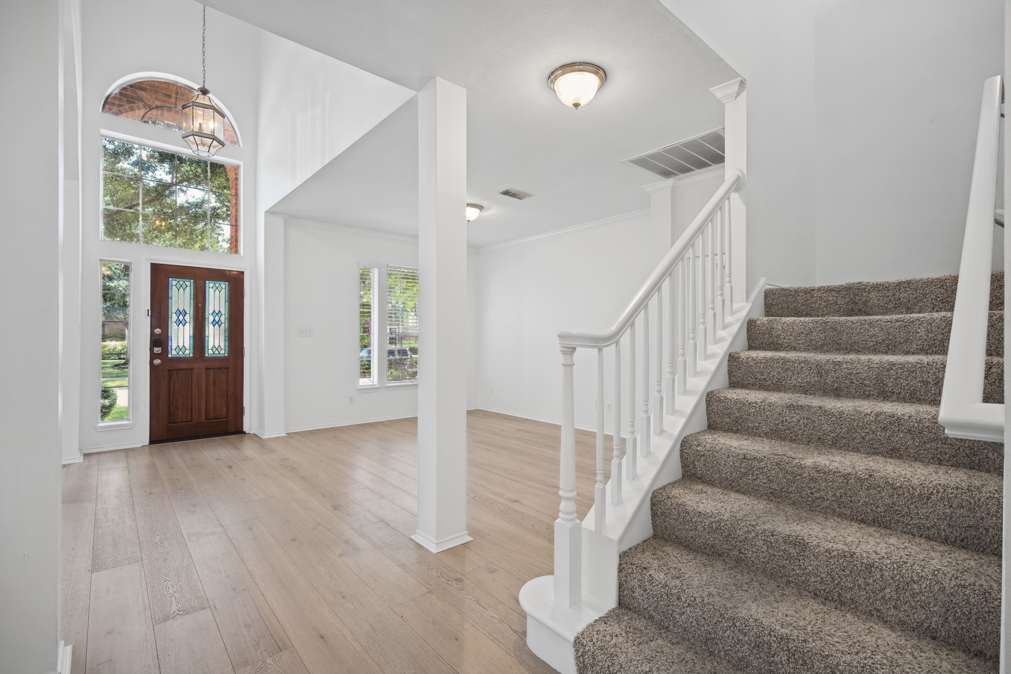 Step inside to a light-filled entry with soaring ceilings, light-toned flooring, and a staircase finished with crisp white railings. Step inside to a light-filled entry with soaring ceilings, light-toned flooring, and a staircase finished with crisp white railings.