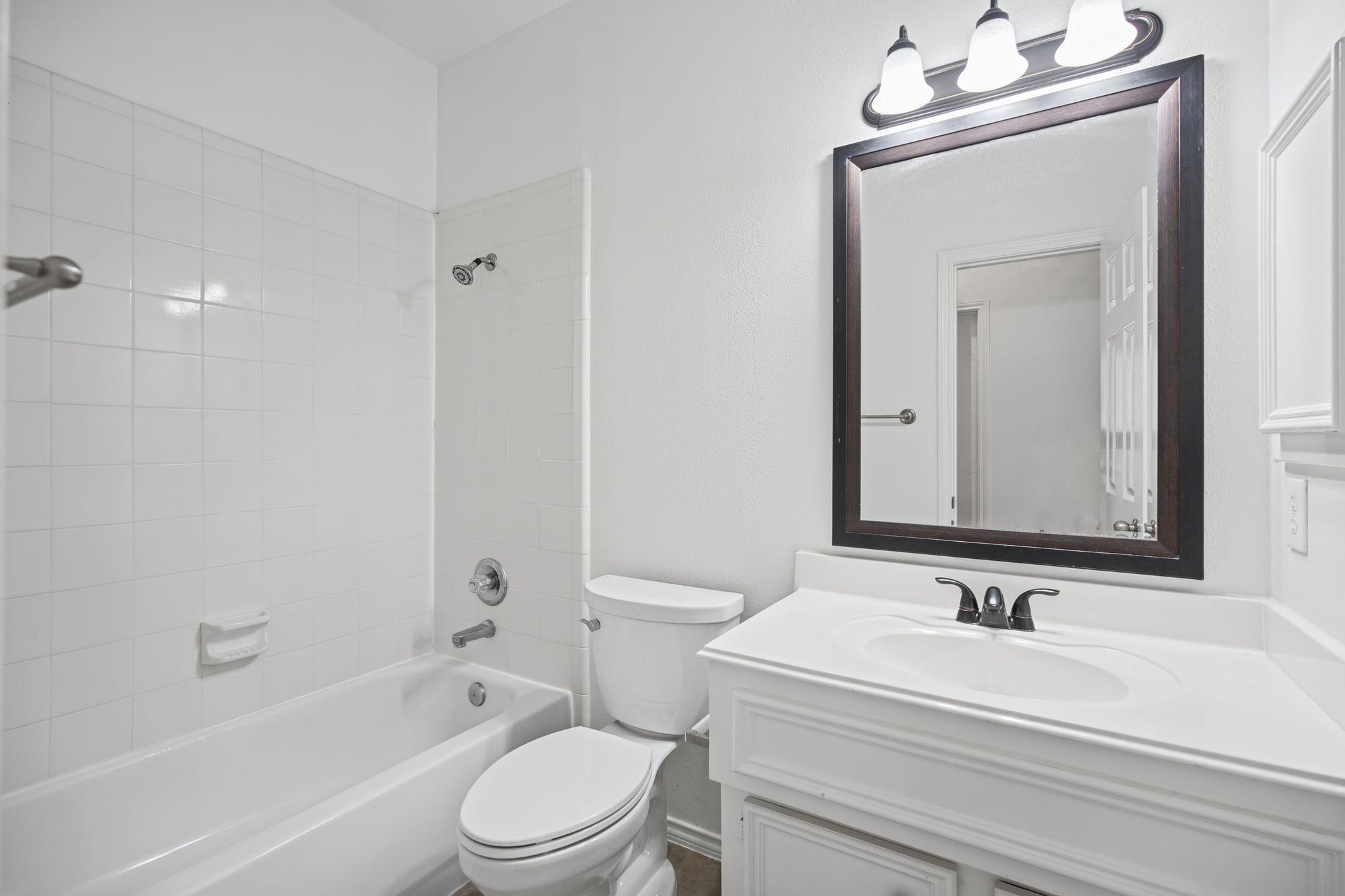 The first-floor bathroom features a white vanity, framed mirror, and a tub-and-shower combination with a tiled surround.