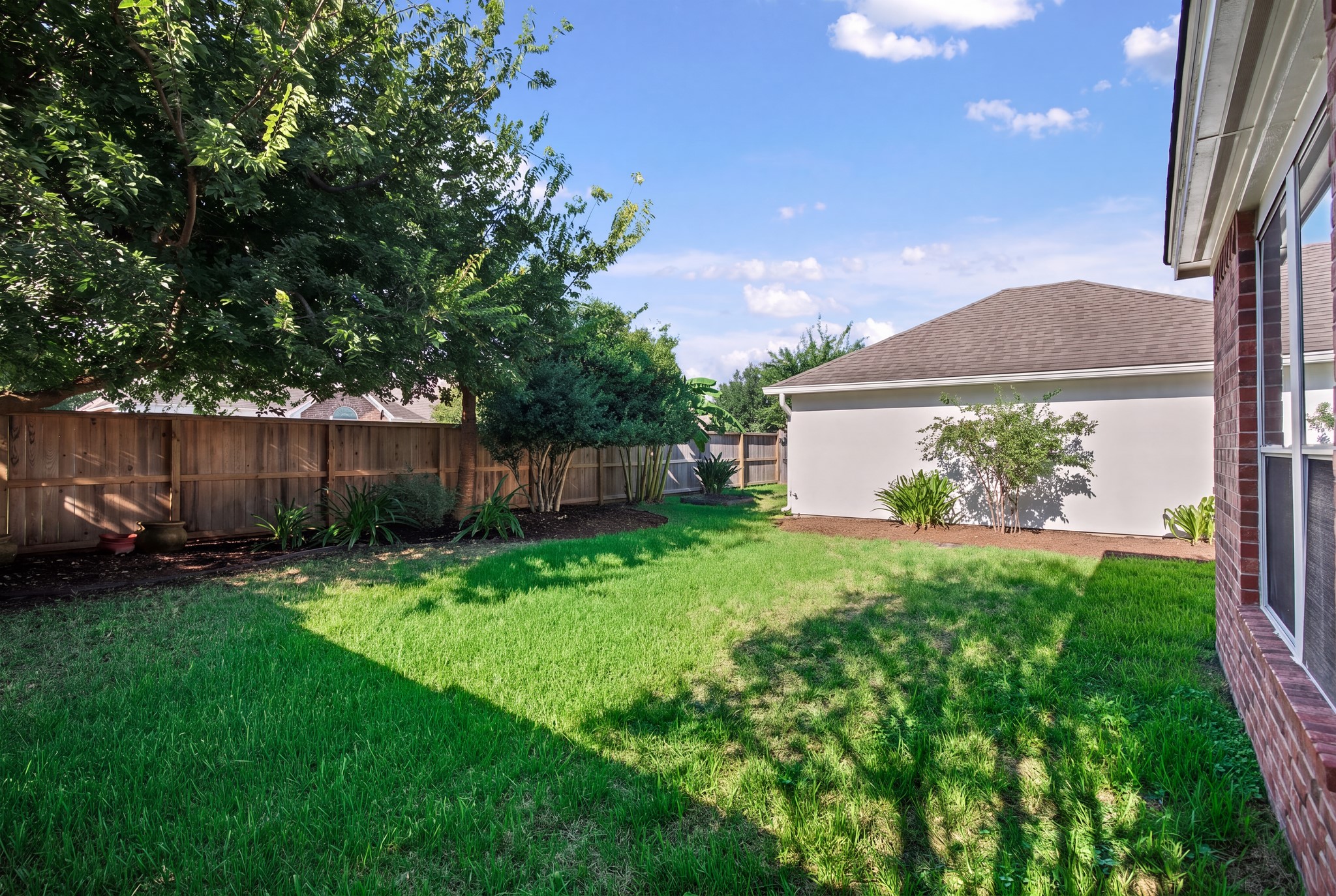 Looking across the backyard, open lawn connects the outdoor spaces surrounding the house and garage.