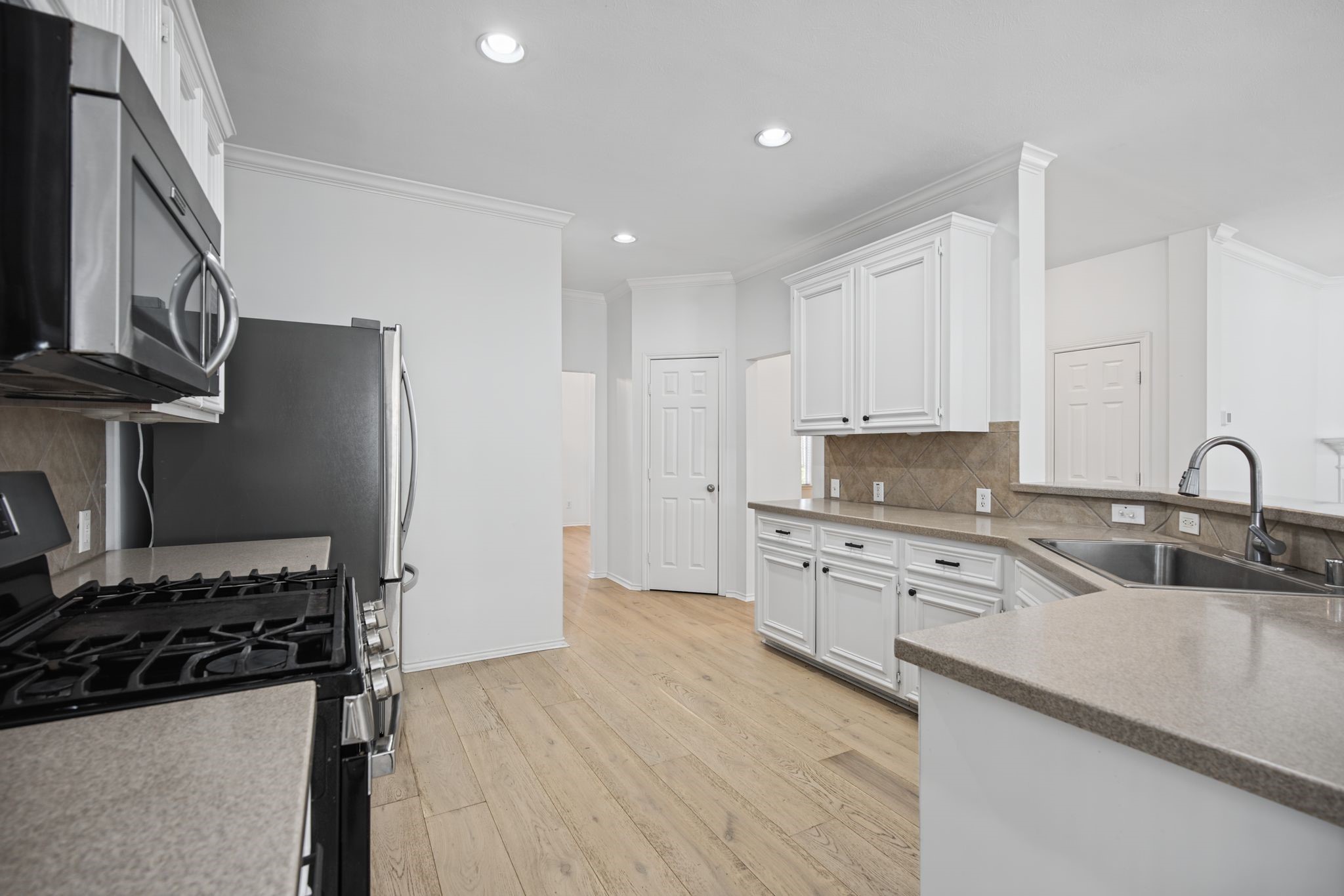 A closer view highlights the gas range and the generous cabinetry and preparation space surrounding the sink.