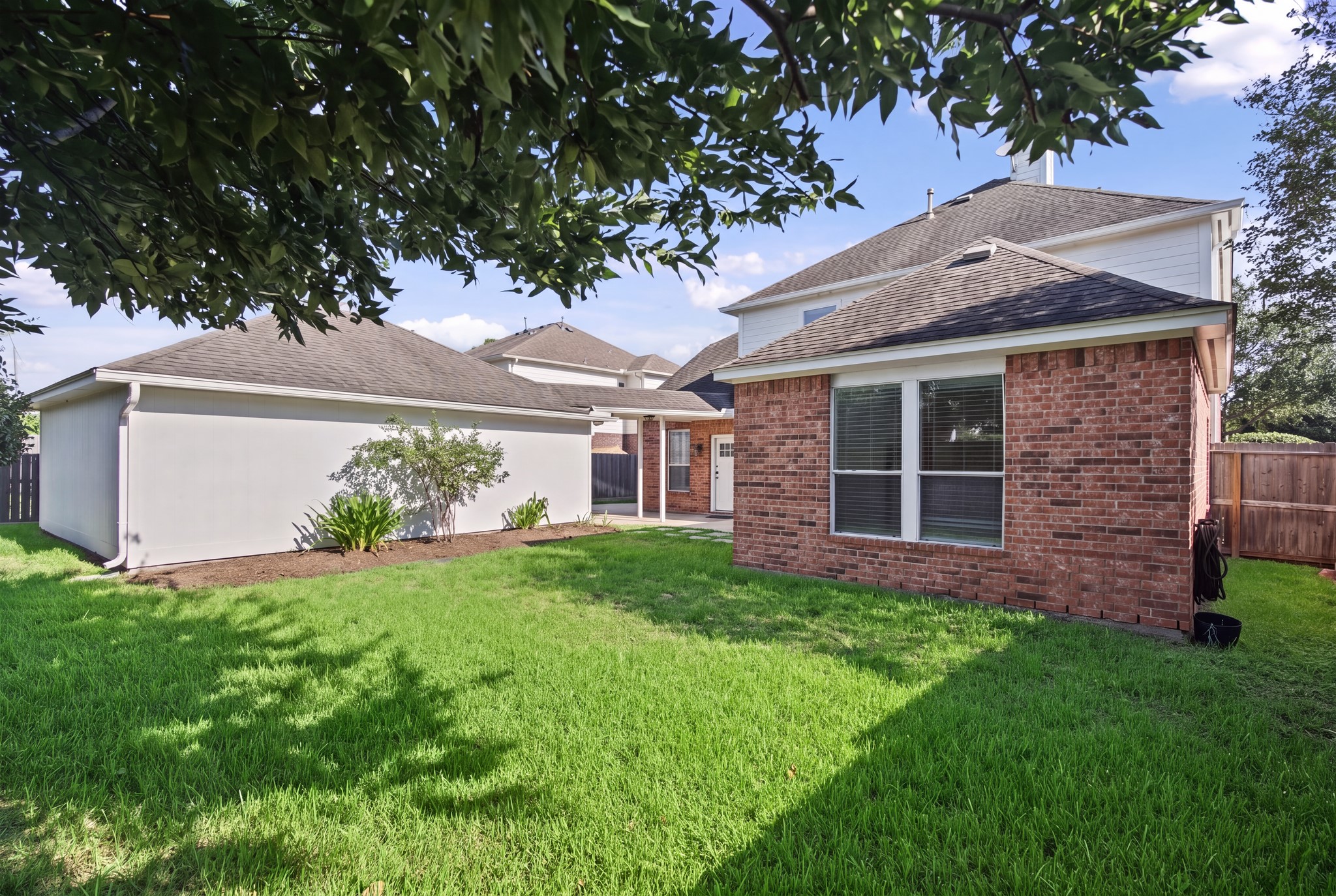 From the lawn, the rear brick exterior and broad windows offer another view of the homes architectural character.