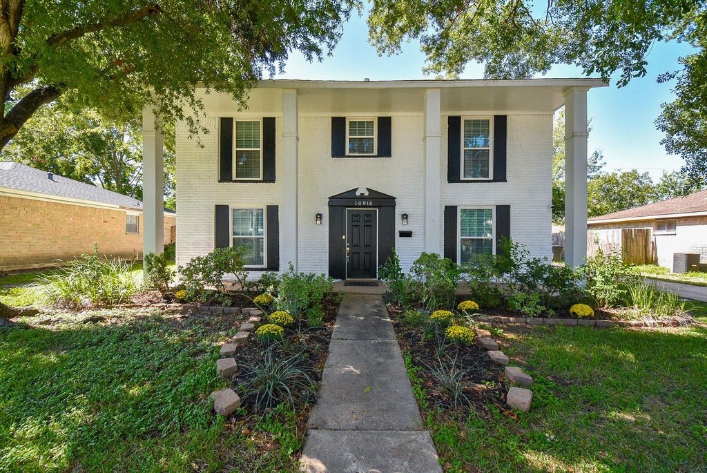 Front view of the home with sprawling front lawn and trees for shade