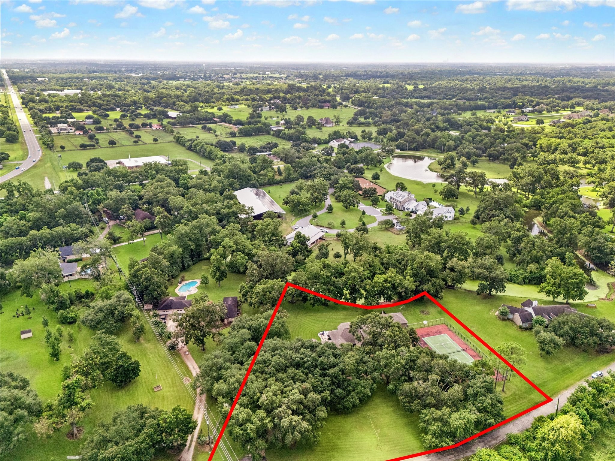 AERIAL VIEW HIGHLIGHTS THE GENEROUSLY SIZED, TREE-FILLED PROPERTY WITH A PRIVATE TENNIS COURT AND SUBSTANTIAL OPEN GREEN SPACE.