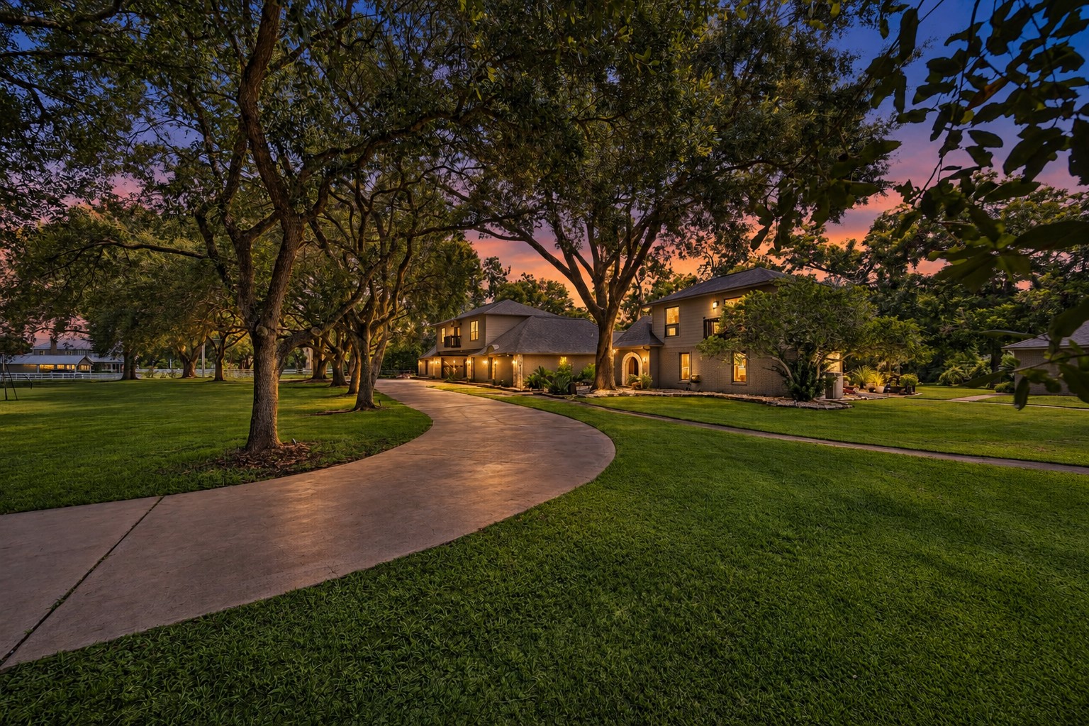 PACIOUS GROUNDS SHOWCASE MATURE SHADE TREES, MANICURED LAWN, AND A CURVED DRIVEWAY LEADING TO THE RESIDENCE.