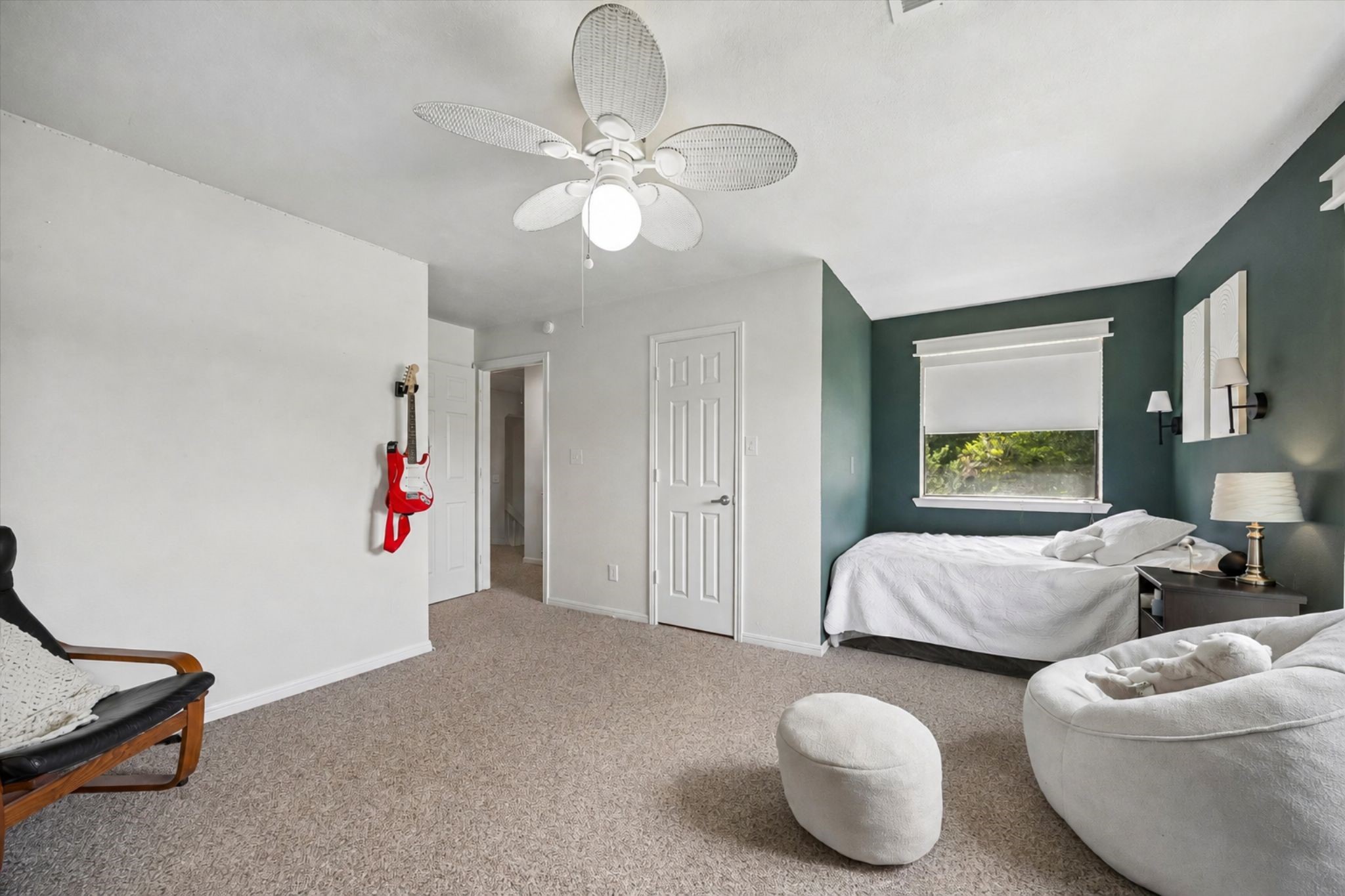 SPACIOUS BEDROOM FEATURES A DISTINCTIVE ACCENT WALL, LARGE WINDOW, CEILING FAN, AND GENEROUS FLOOR SPACE.