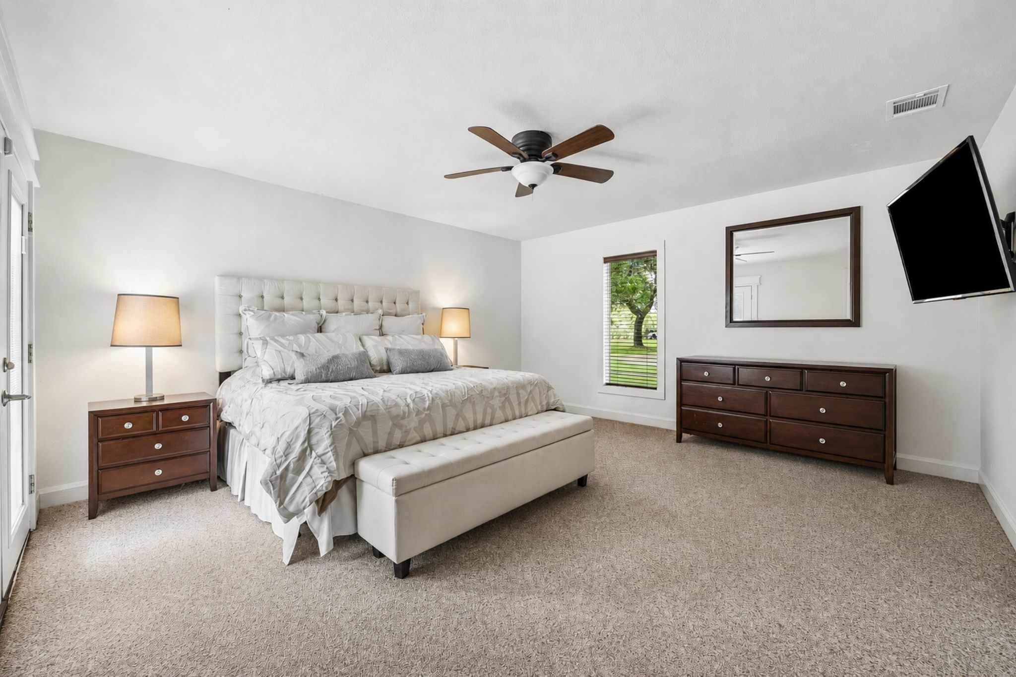 PRIVATE TENNIS COURT SURROUNDED BY EXPANSIVE LAWN AND MATURE TREES, CREATING A SPACIOUS OUTDOOR RECREATION AREA.