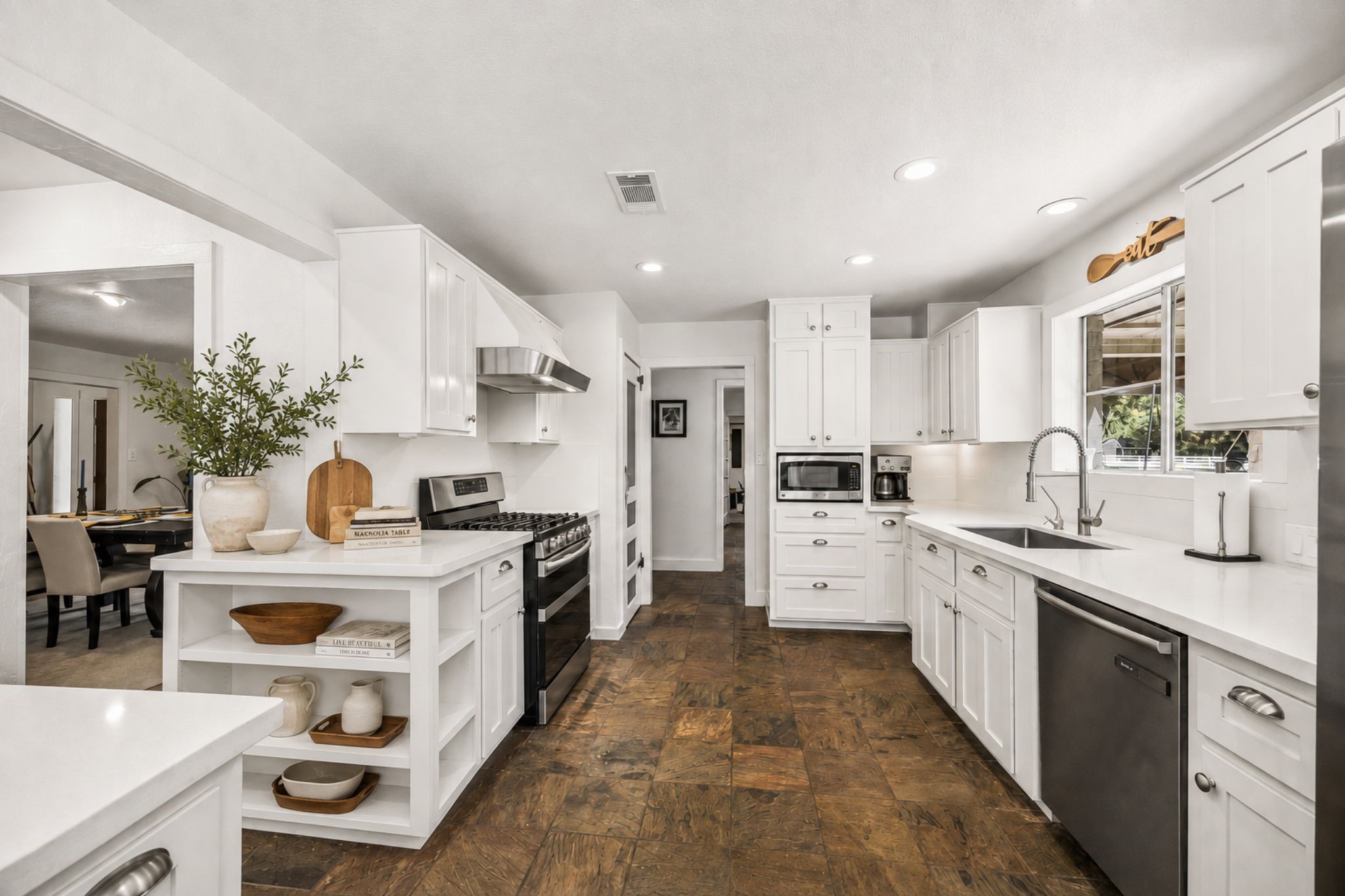 UPDATED KITCHEN FEATURES EXTENSIVE WHITE CABINETRY, SOLID-SURFACE COUNTERS, STAINLESS STEEL APPLIANCES, GAS COOKING, AND RECESSED LIGHTING.