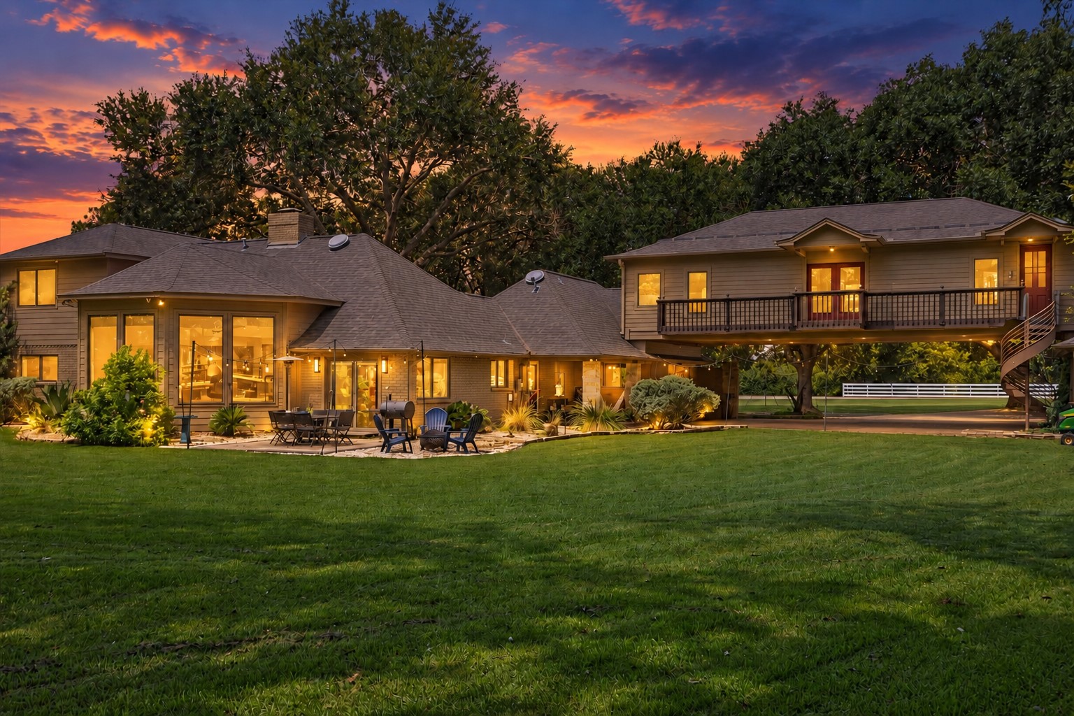 REAR VIEW HIGHLIGHTS THE HOMES EXPANSIVE FOOTPRINT, LARGE LAWN, PATIO AREA, AND ELEVATED SECOND-STORY SECTION WITH BALCONY ACCESS.