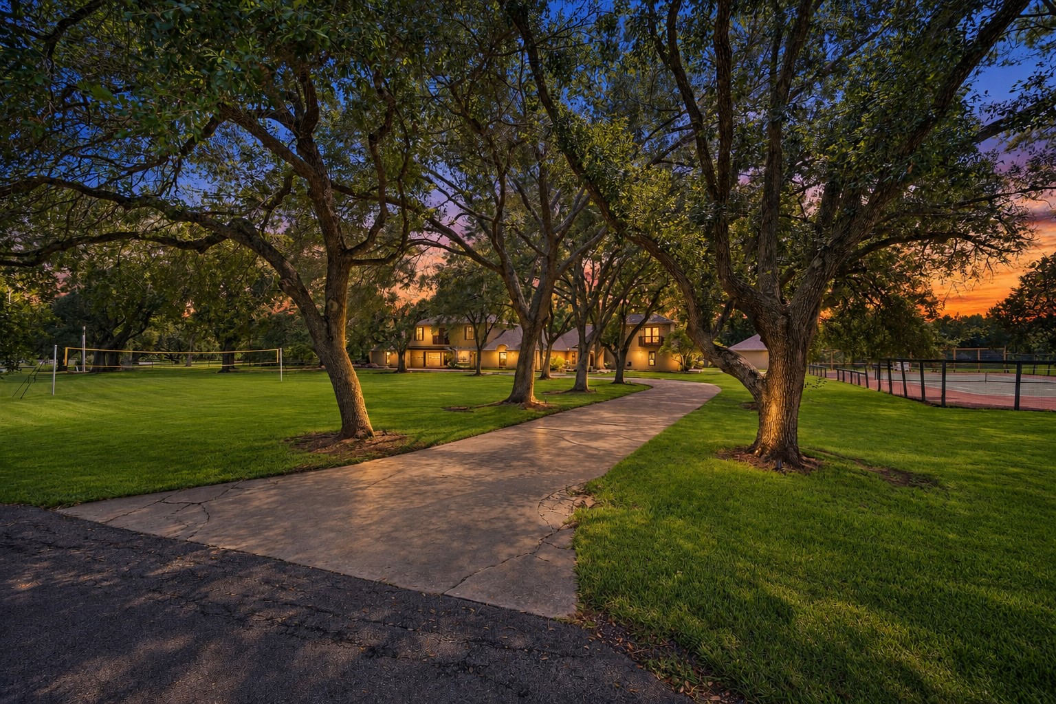 LONG, TREE-LINED DRIVEWAY WINDS THROUGH THE PROPERTY, PROVIDING A SHADED APPROACH SURROUNDED BY MATURE LANDSCAPING.