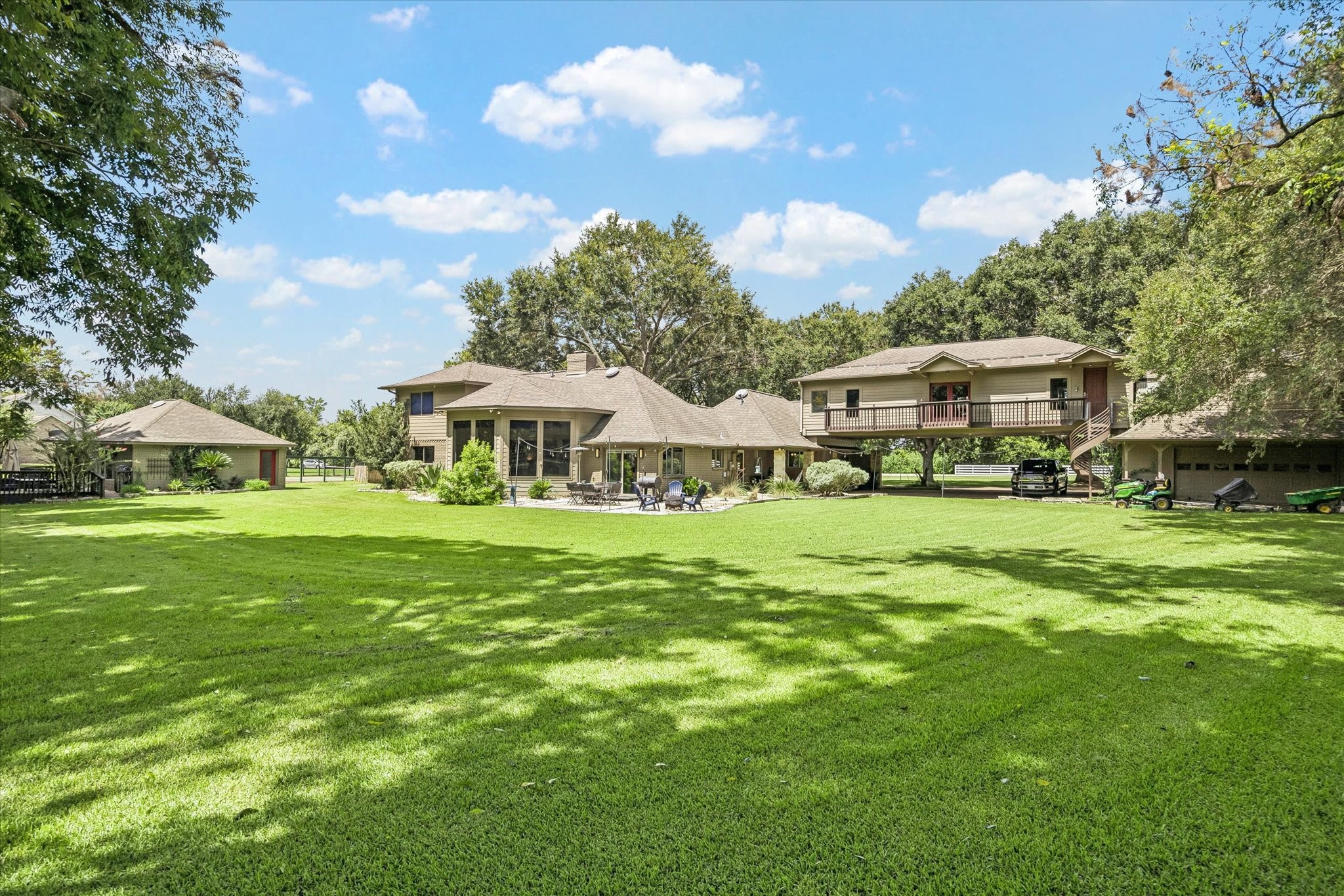 WIDE REAR VIEW SHOWCASES THE HOME, EXPANSIVE GROUNDS, MATURE LANDSCAPING, AND MULTIPLE EXTERIOR STRUCTURES.