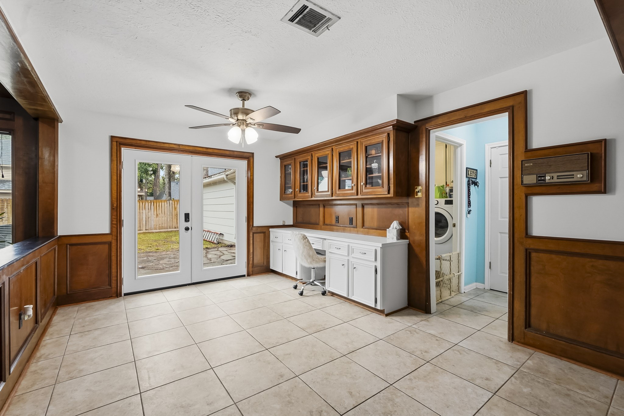 Breakfast nook area with elegant wood paneling, built-in cabinetry, and natural light from French doors leading to a fenced backyard.