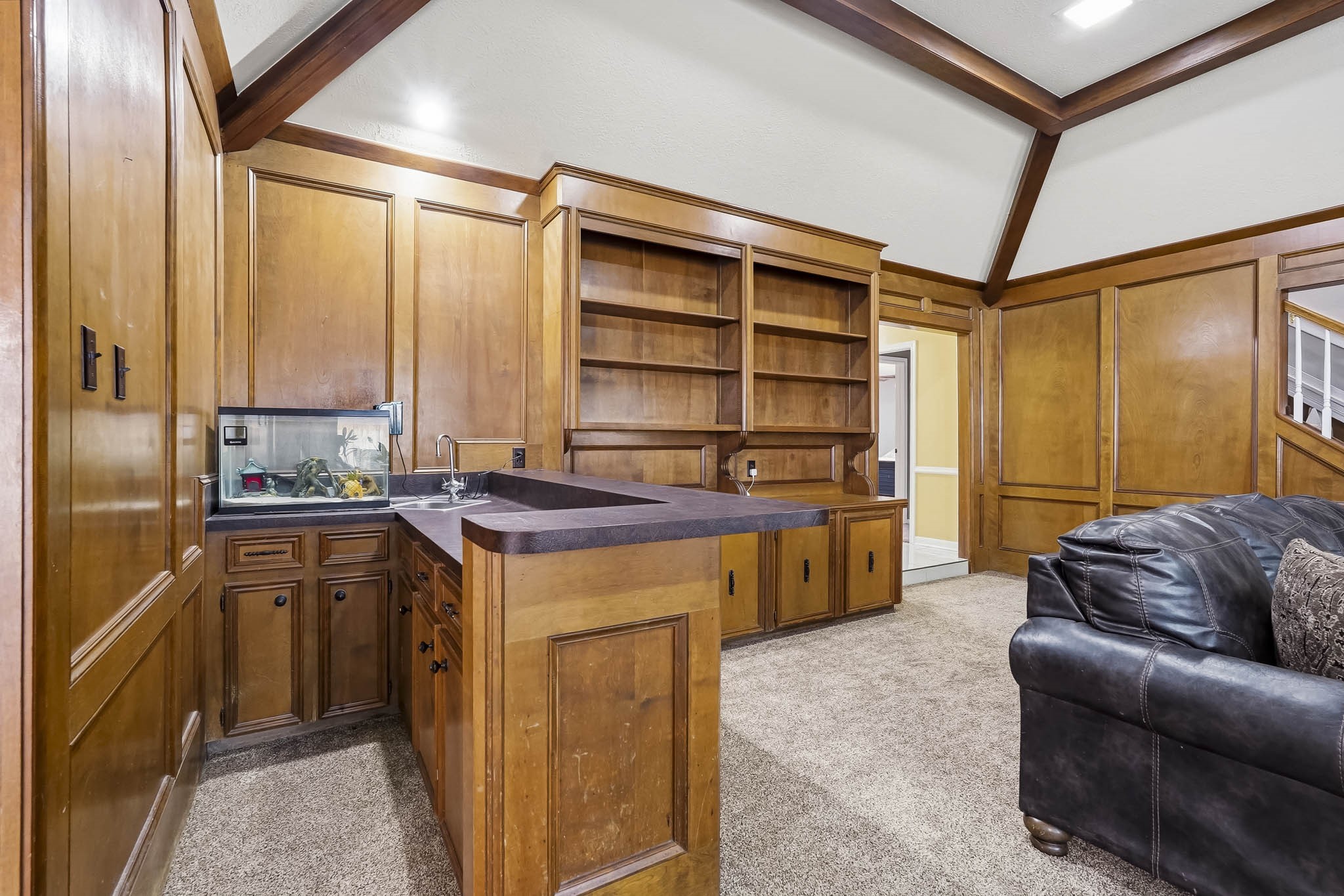 Charming den with rich wood paneling, built-in shelving, and a wet bar, ideal for entertaining or relaxing.