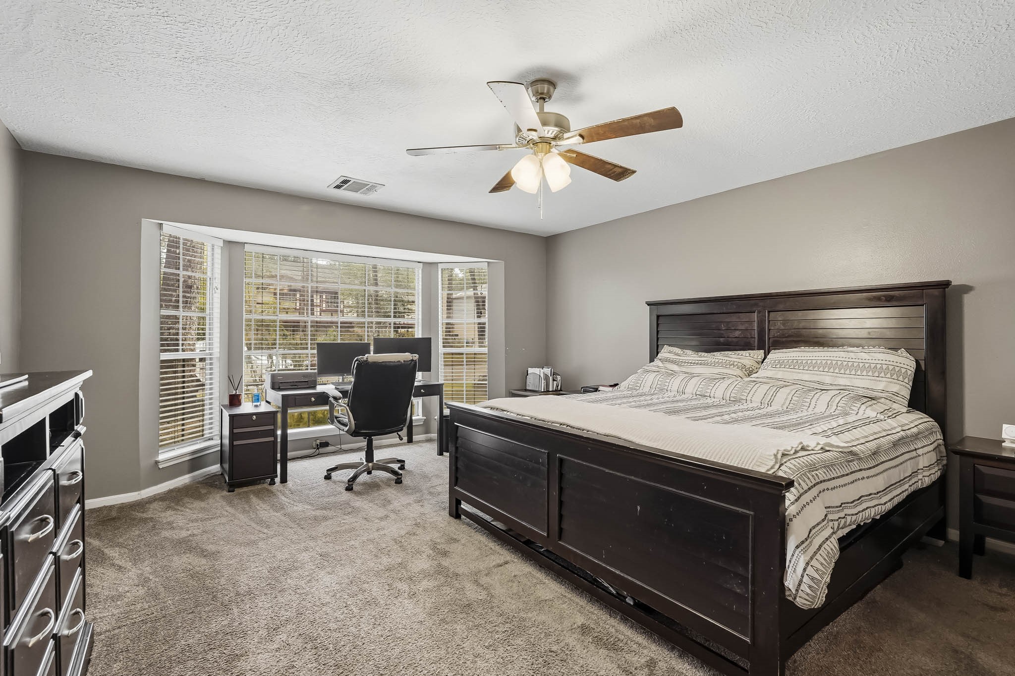 Spacious primary bedroom with soft carpeting and a large bay window offering abundant natural light.
