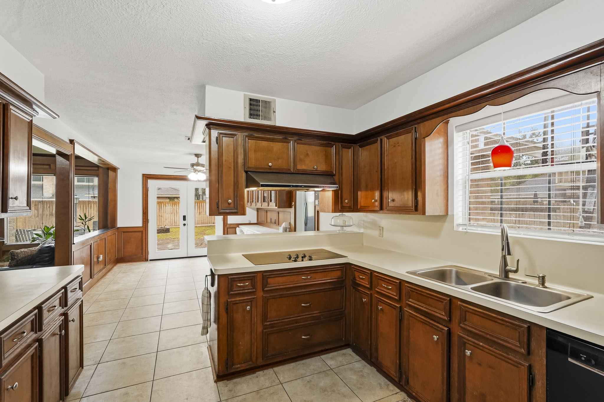 Charming kitchen with rich wood cabinetry, tile flooring, and ample natural light, seamlessly leading to a cozy breakfast nook area with a view of the backyard.