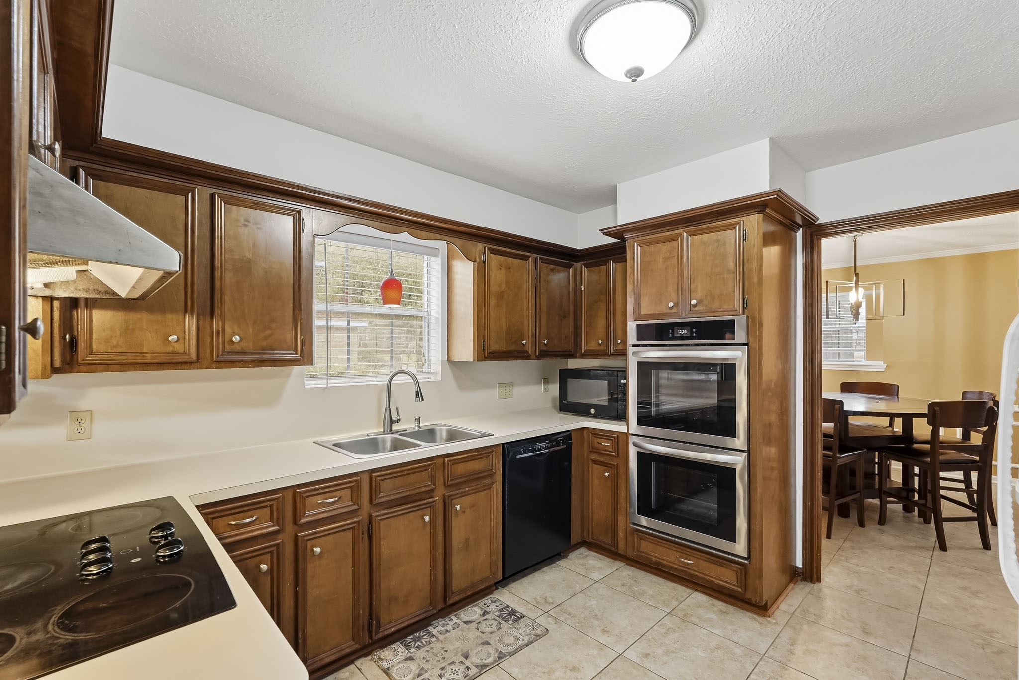 Charming kitchen with rich wooden cabinetry, modern double ovens.