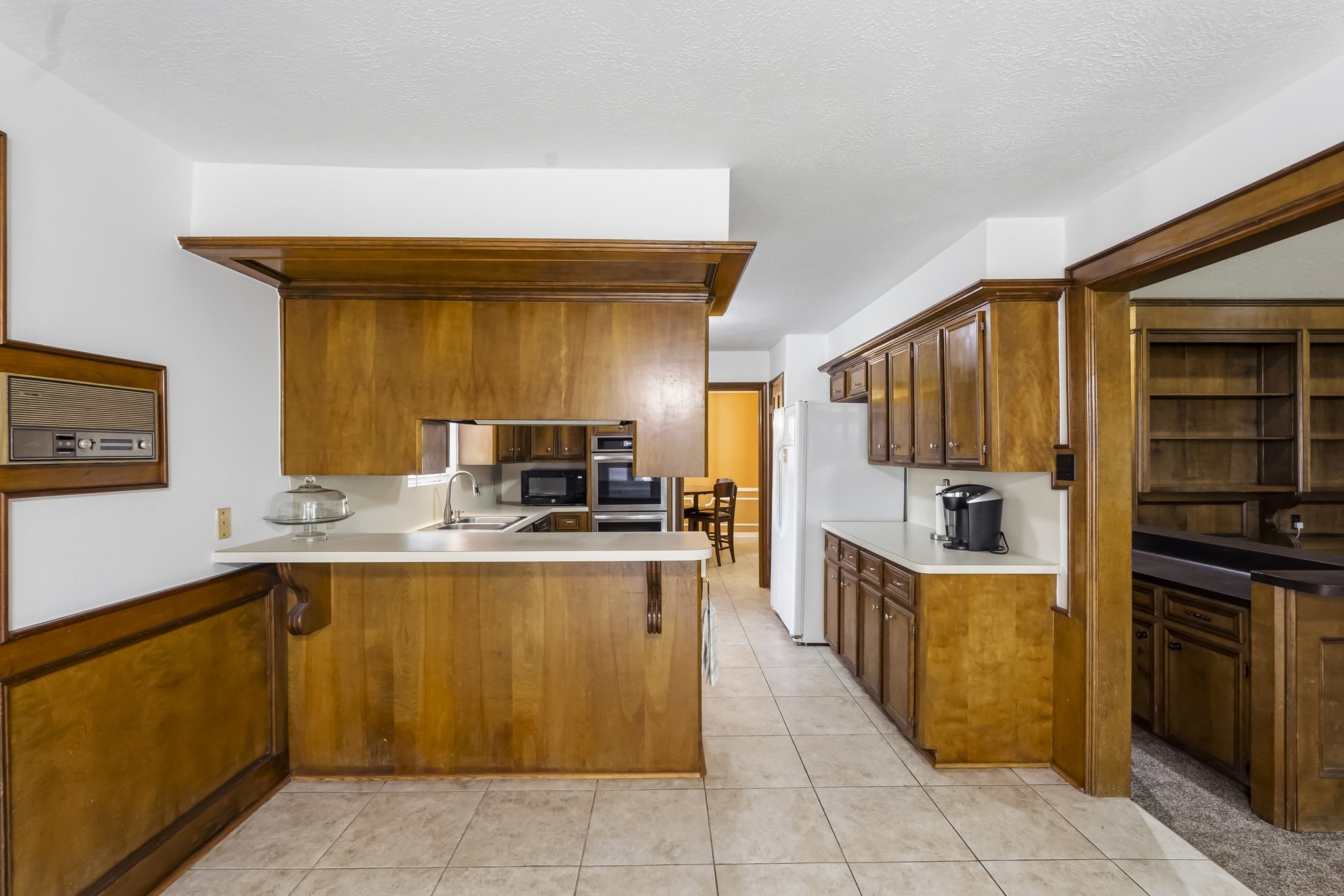 Charming kitchen with rich wood cabinetry, ample counter space, and a cozy breakfast bar, seamlessly connecting to a well-lit dining area.
