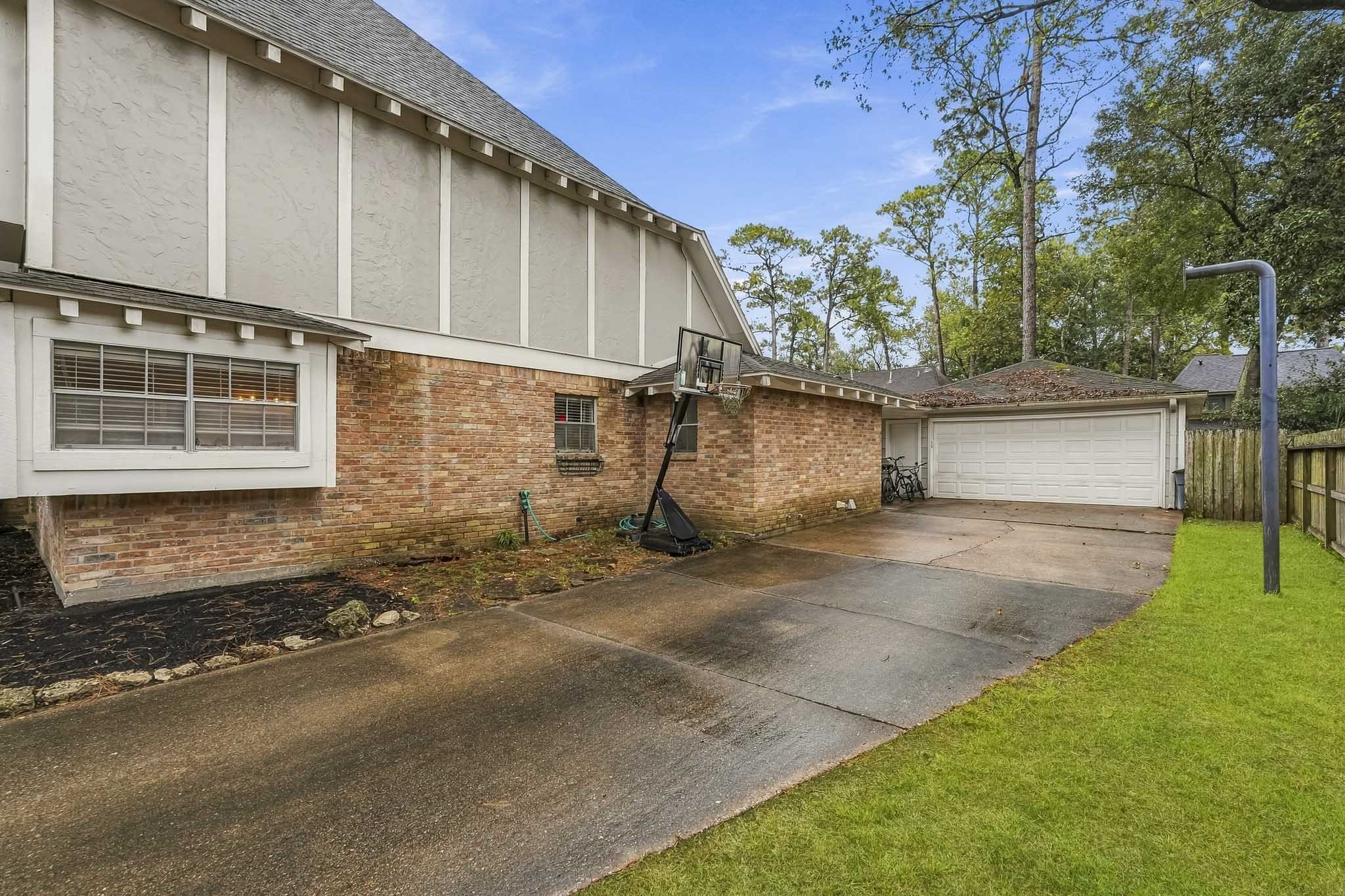 Charming home with a spacious driveway leading to a two-car garage, surrounded by mature trees and a well-maintained lawn.