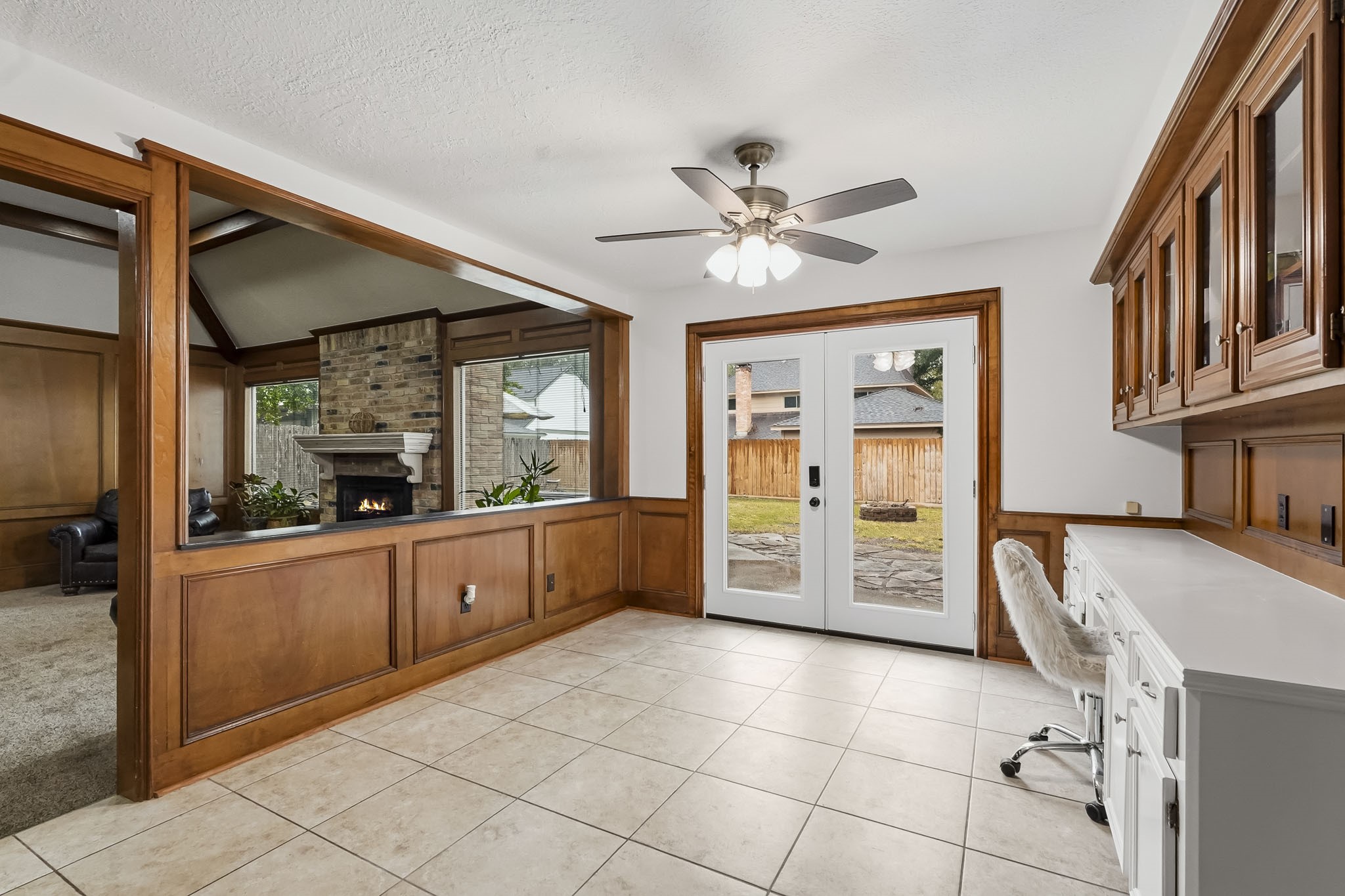 Bright and inviting space featuring elegant wood paneling and built-in cabinetry, with French doors leading to the backyard.