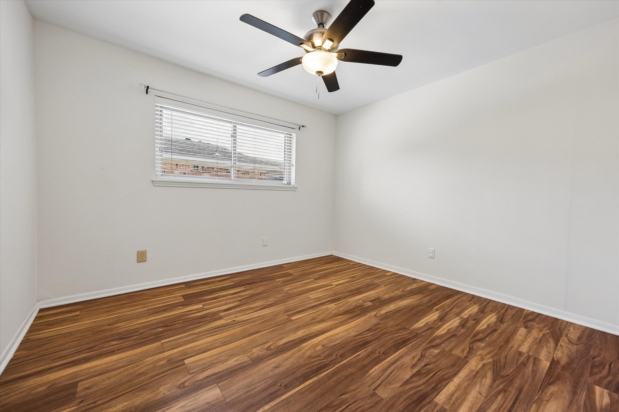 Another guest bedroom featuring durable wood-look laminate flooring and a ceiling fan. No carpet in this home!