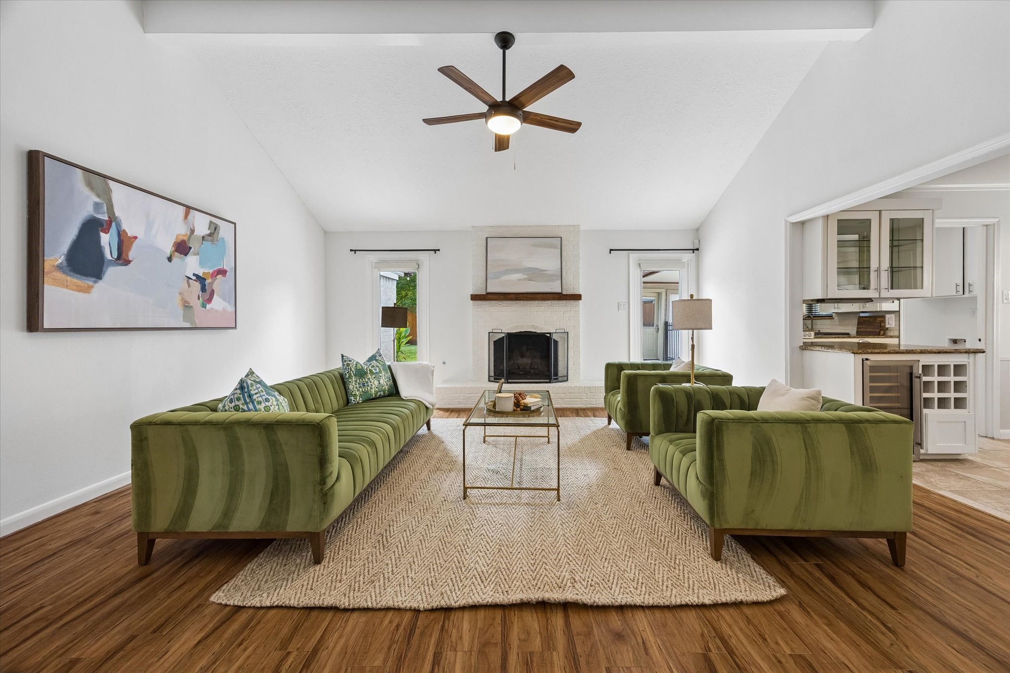 Soaring vaulted ceilings and a classic brick fireplace highlight the main living space, where custom-shaded windows invite in abundant natural light.
