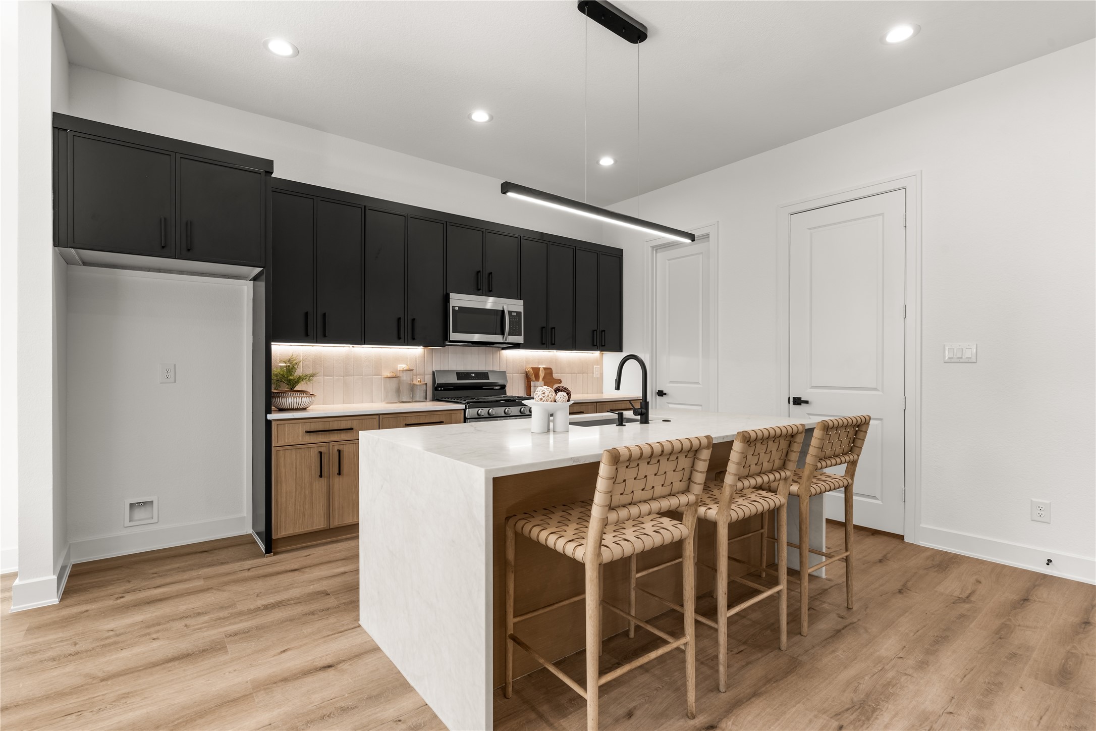 Designed to accommodate both culinary pursuits and effortless entertaining, the kitchen centers around a generous island with integrated sink and breakfast seating.