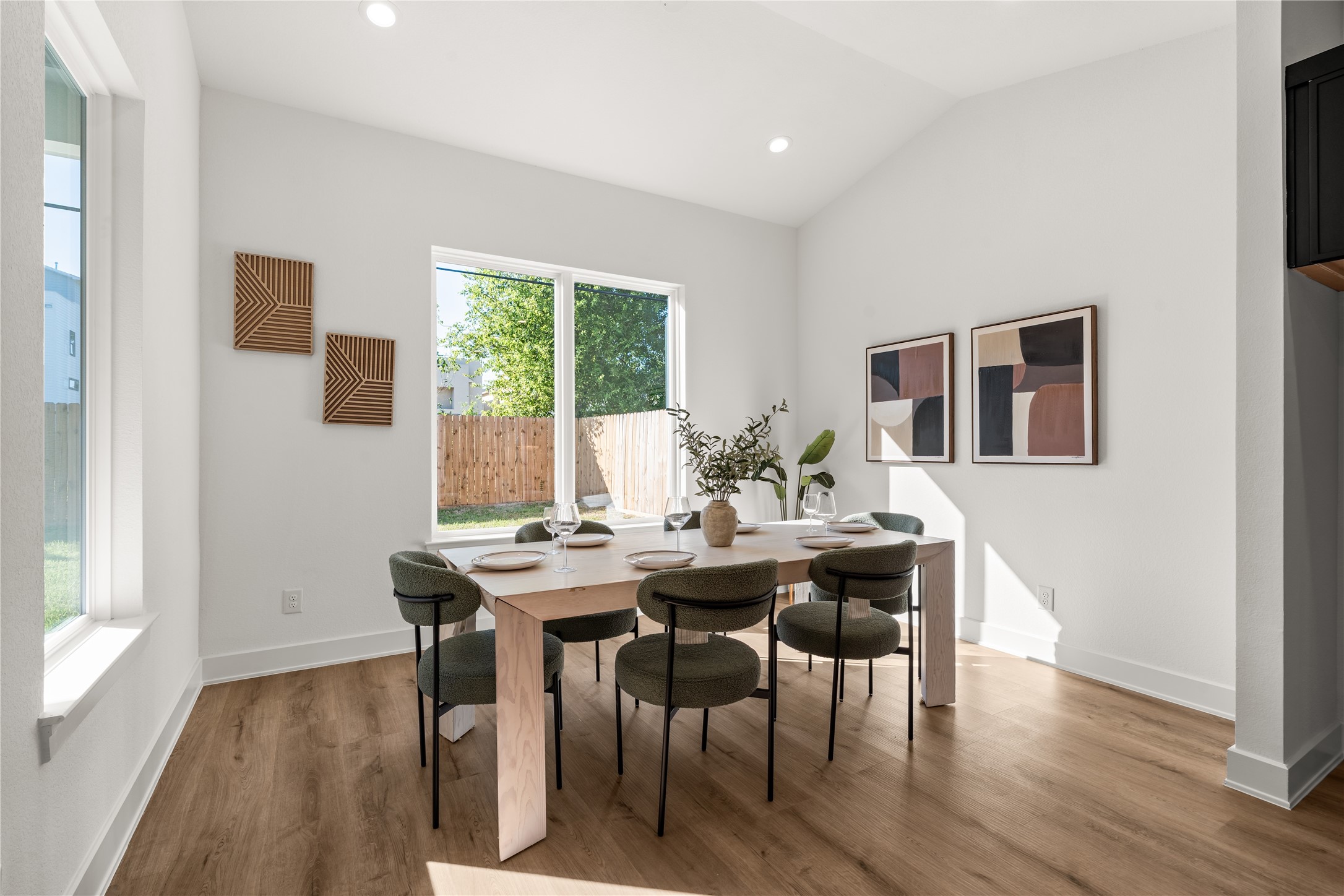 A subtly vaulted ceiling introduces architectural volume to the dining room, creating an airy atmosphere enhanced by expansive windows and abundant natural light.