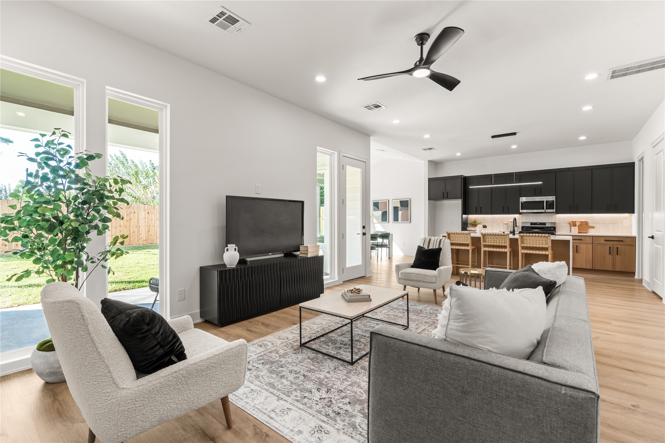 The living room transitions naturally into the kitchen, where a generous island establishes a subtle distinction between spaces without interrupting their openness.