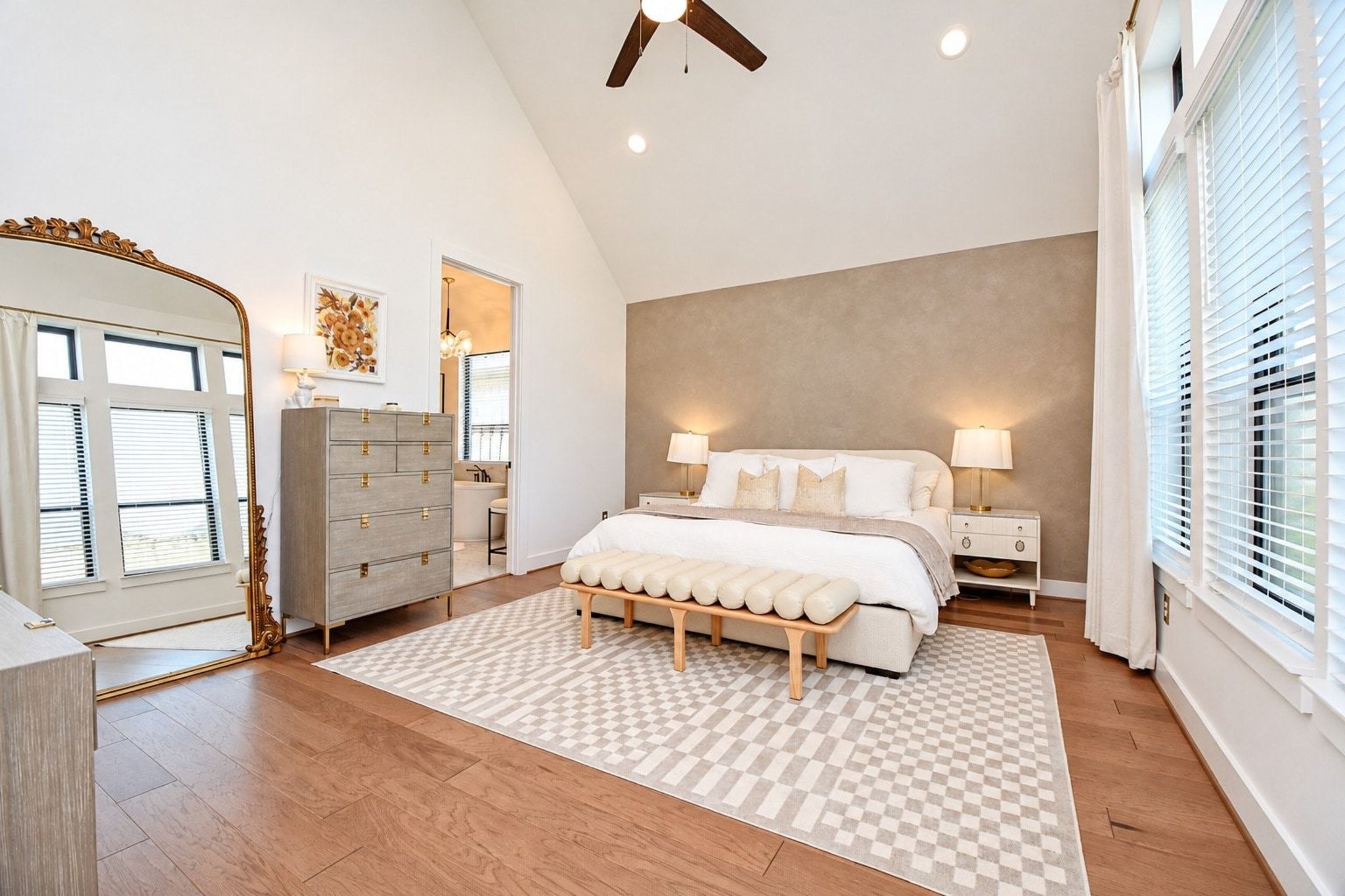 Spacious and serene bedroom featuring a vaulted ceiling, large windows with abundant natural light, and a cozy, modern design with soft neutral tones.