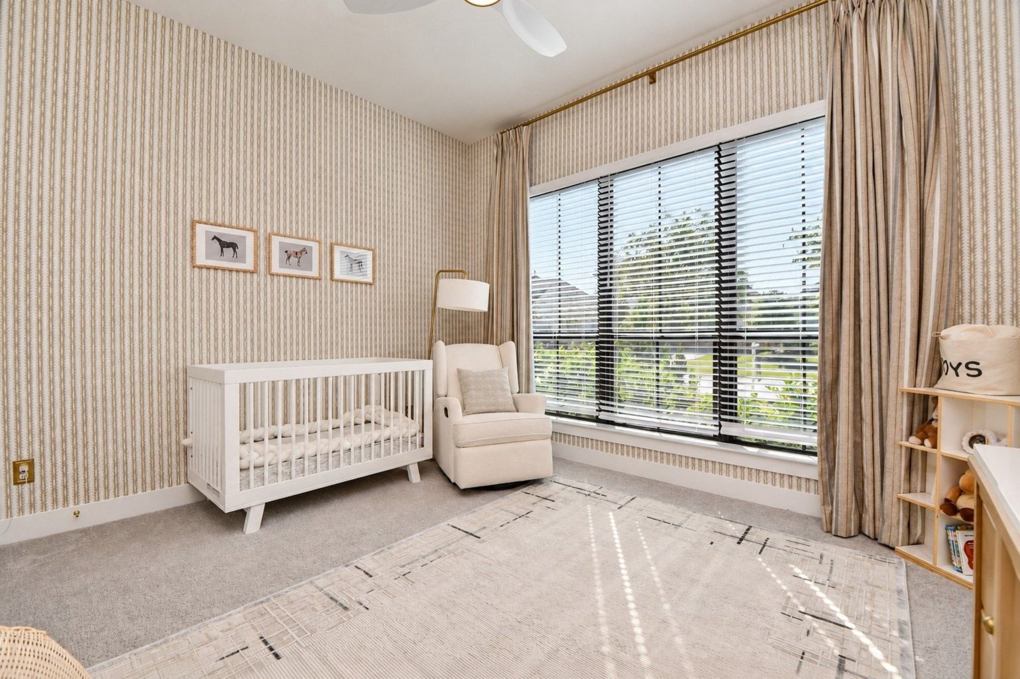 Accented with neutral striped wallpaper and large windows that flood the room with natural light.  Built-in custom shelves.
