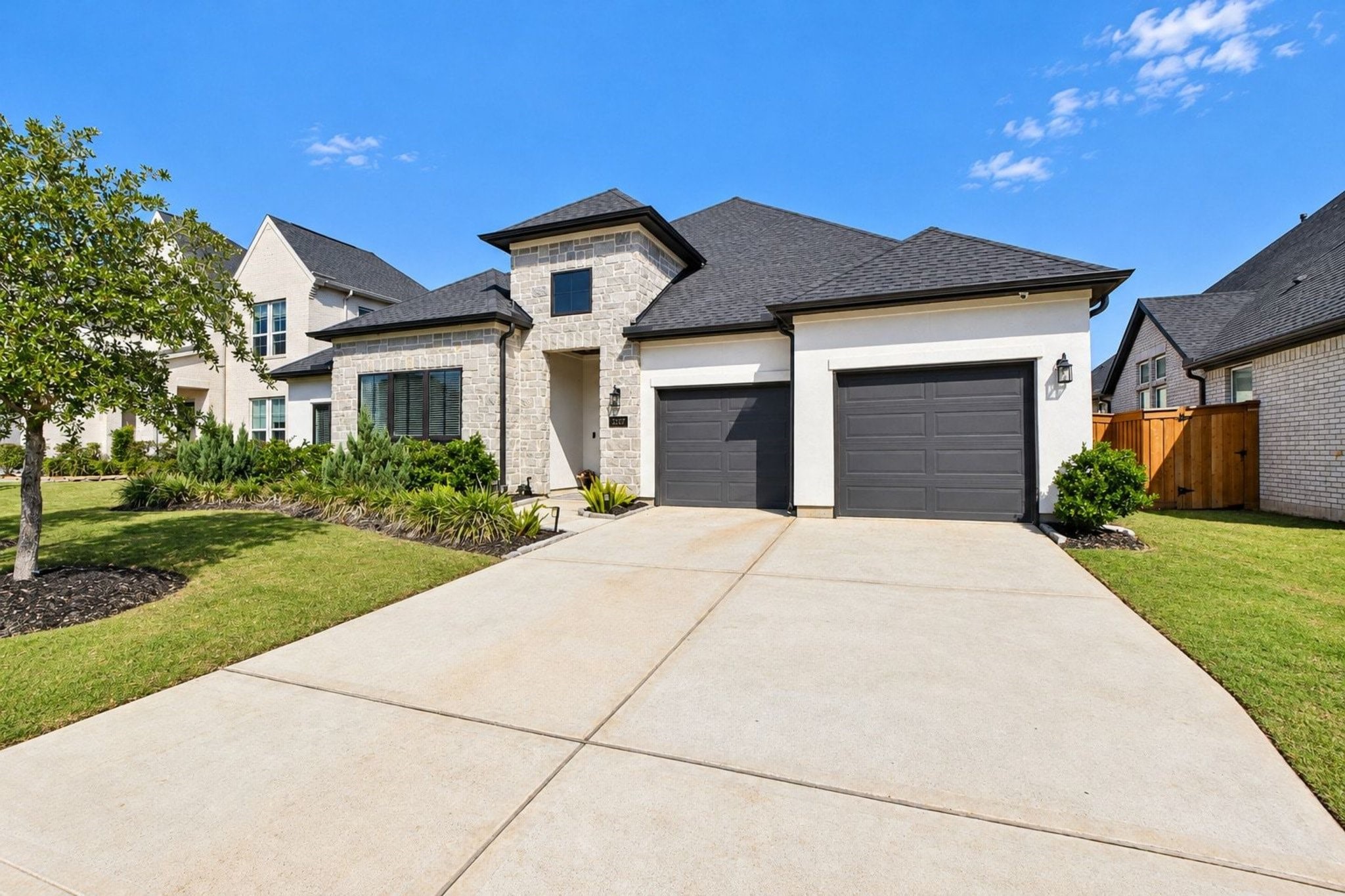 Stunning modern home with a sleek facade, featuring two spacious garages and manicured landscaping, set in a desirable neighborhood.
