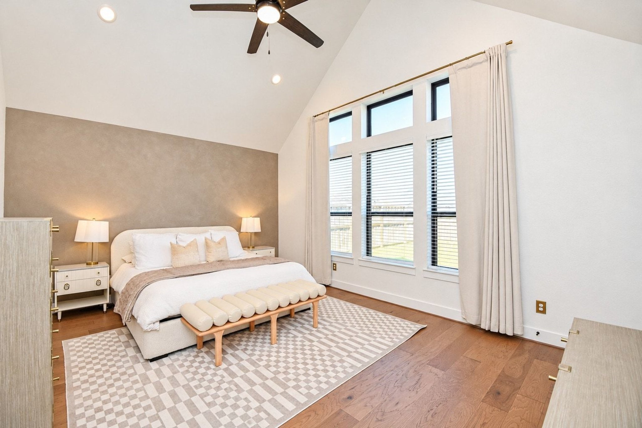 Spacious bedroom with vaulted ceilings, abundant natural light from large windows, and elegant neutral decor for a serene retreat.