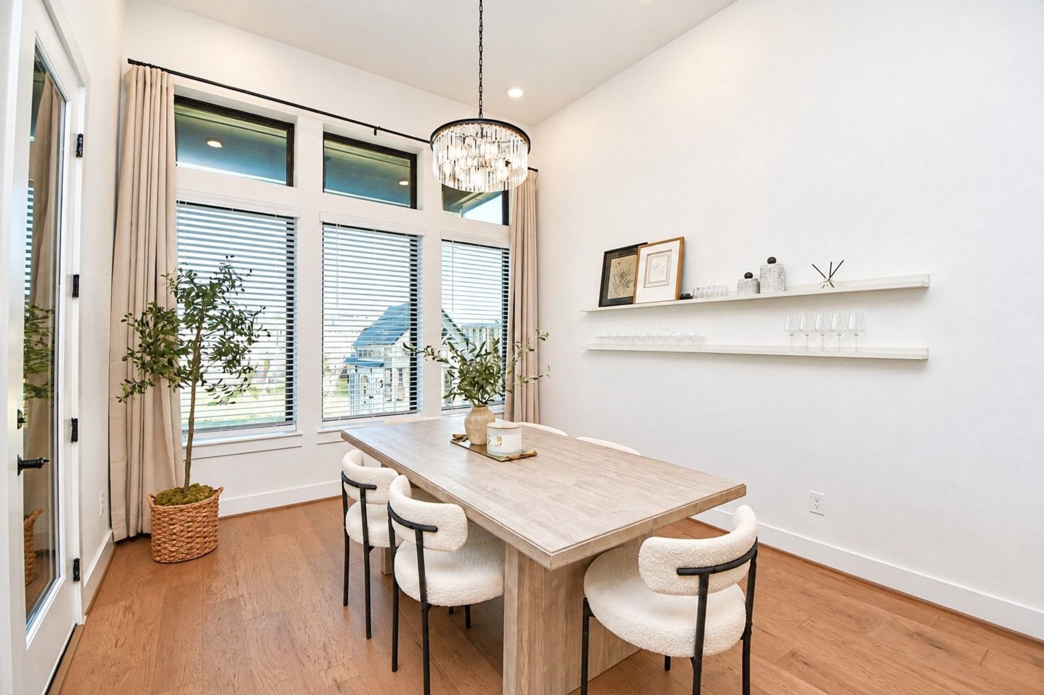 Elegant dining area with large windows for natural light, featuring a modern chandelier and built-in shelving.