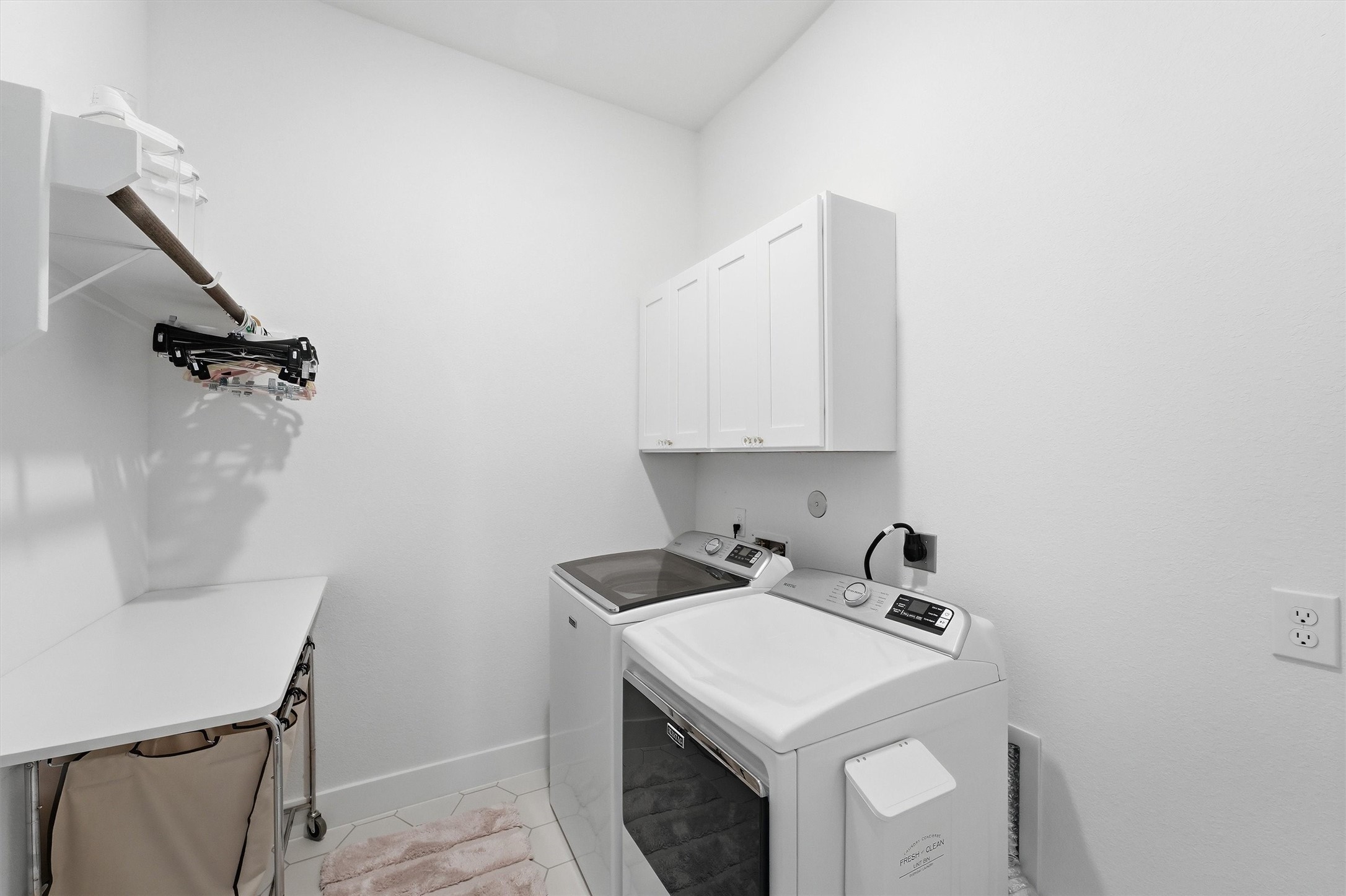 Built-in cabinetry provides convenient storage for laundry supplies and household essentials. A dedicated folding bar offers valuable workspace for sorting and folding.