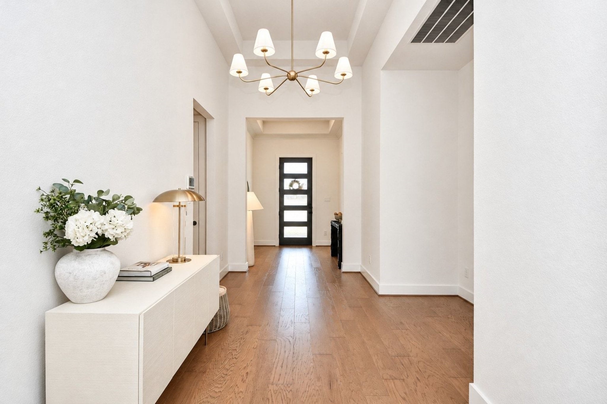Dramatic and spacious entryway featuring a modern chandelier and hardwood floors.