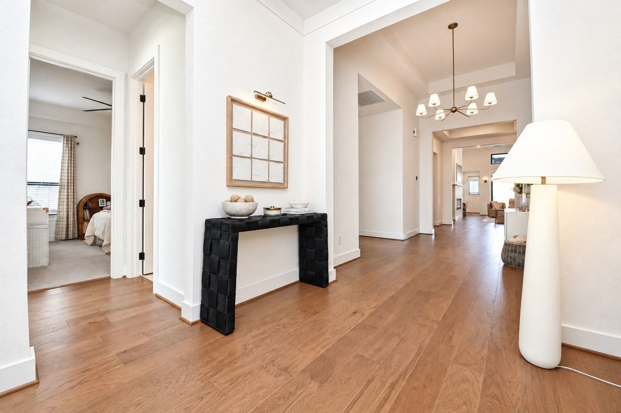 Inviting entryway with warm wooden floors and modern lighting, leading to a spacious, light-filled living area.