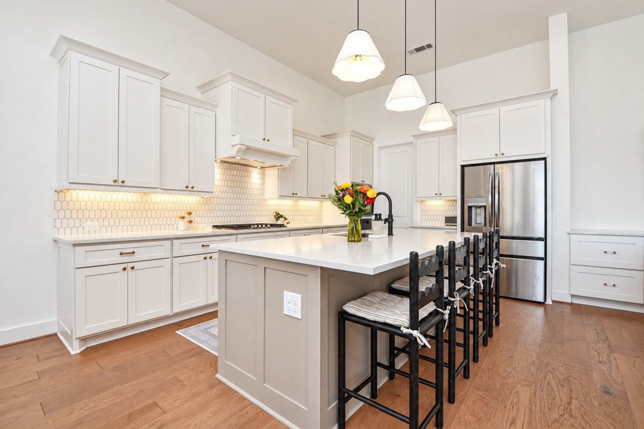 Bright and spacious kitchen with sleek white cabinetry, modern stainless steel appliances, and a large island with seating, perfect for entertaining and meal prep.