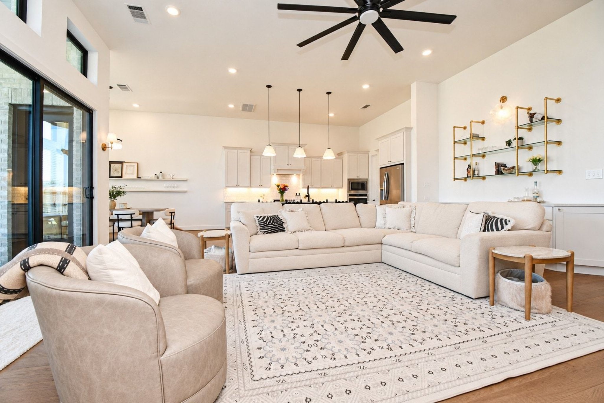 Open living area that seamlessly connected to a sleek kitchen with pendant lighting and stainless steel appliances.