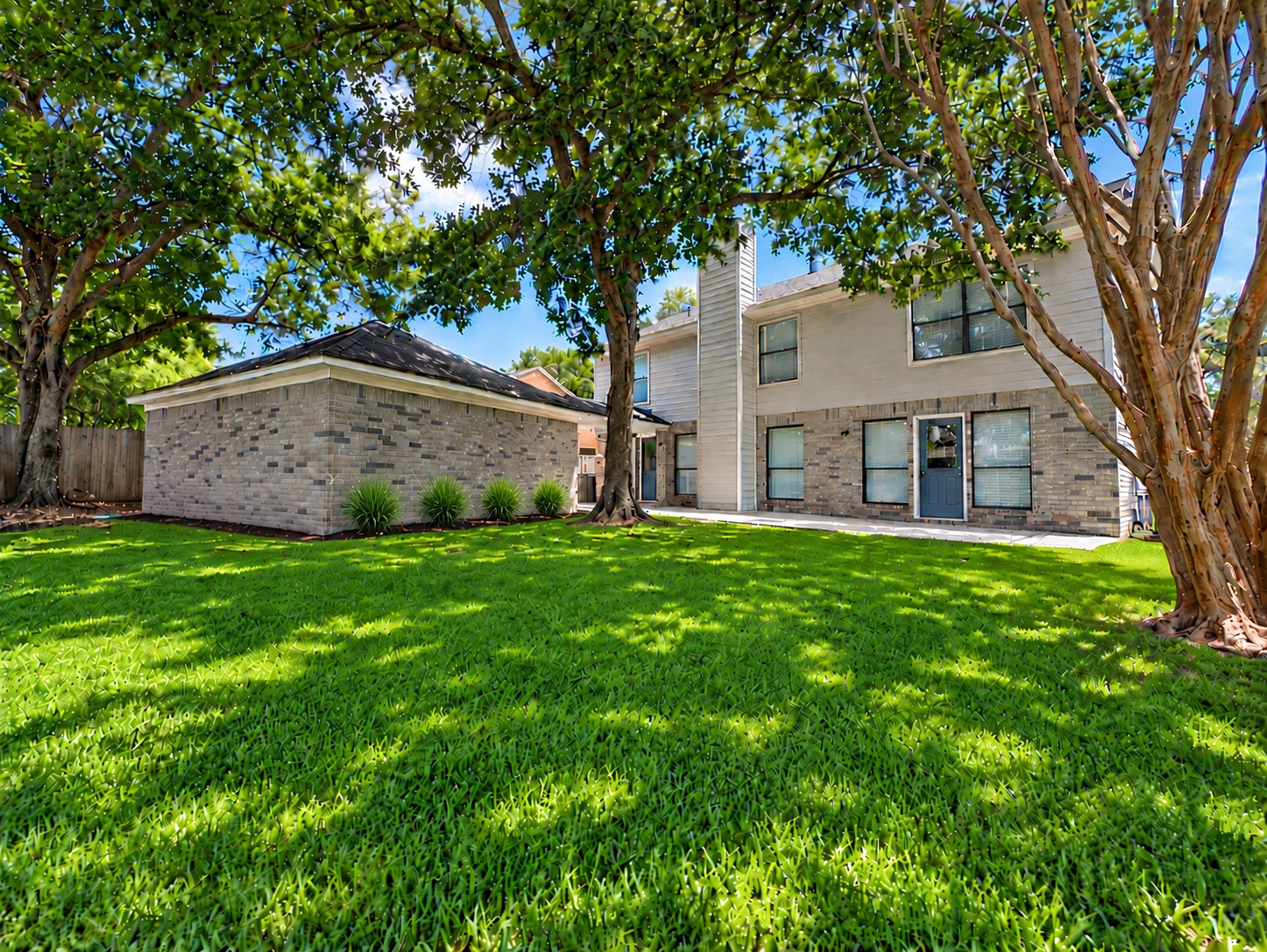 Spacious backyard with mature shade trees, lush green lawn, and plenty of room for outdoor activities.