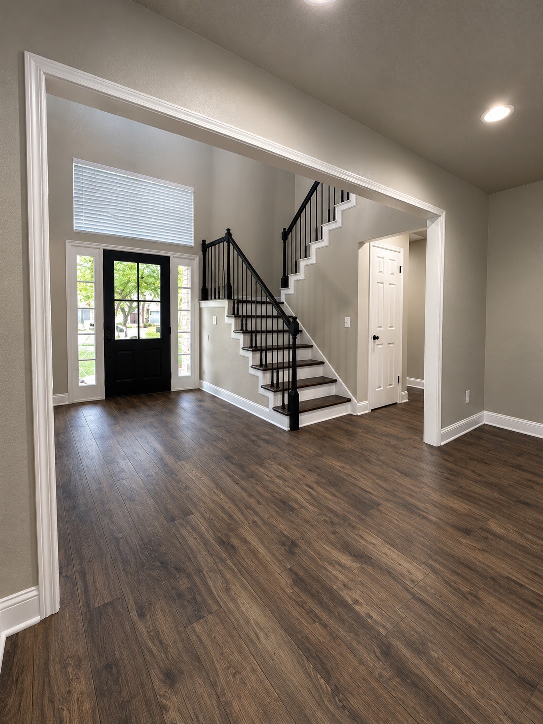 View from the living room highlighting the beautiful entryway, elegant staircase, and open floor plan.