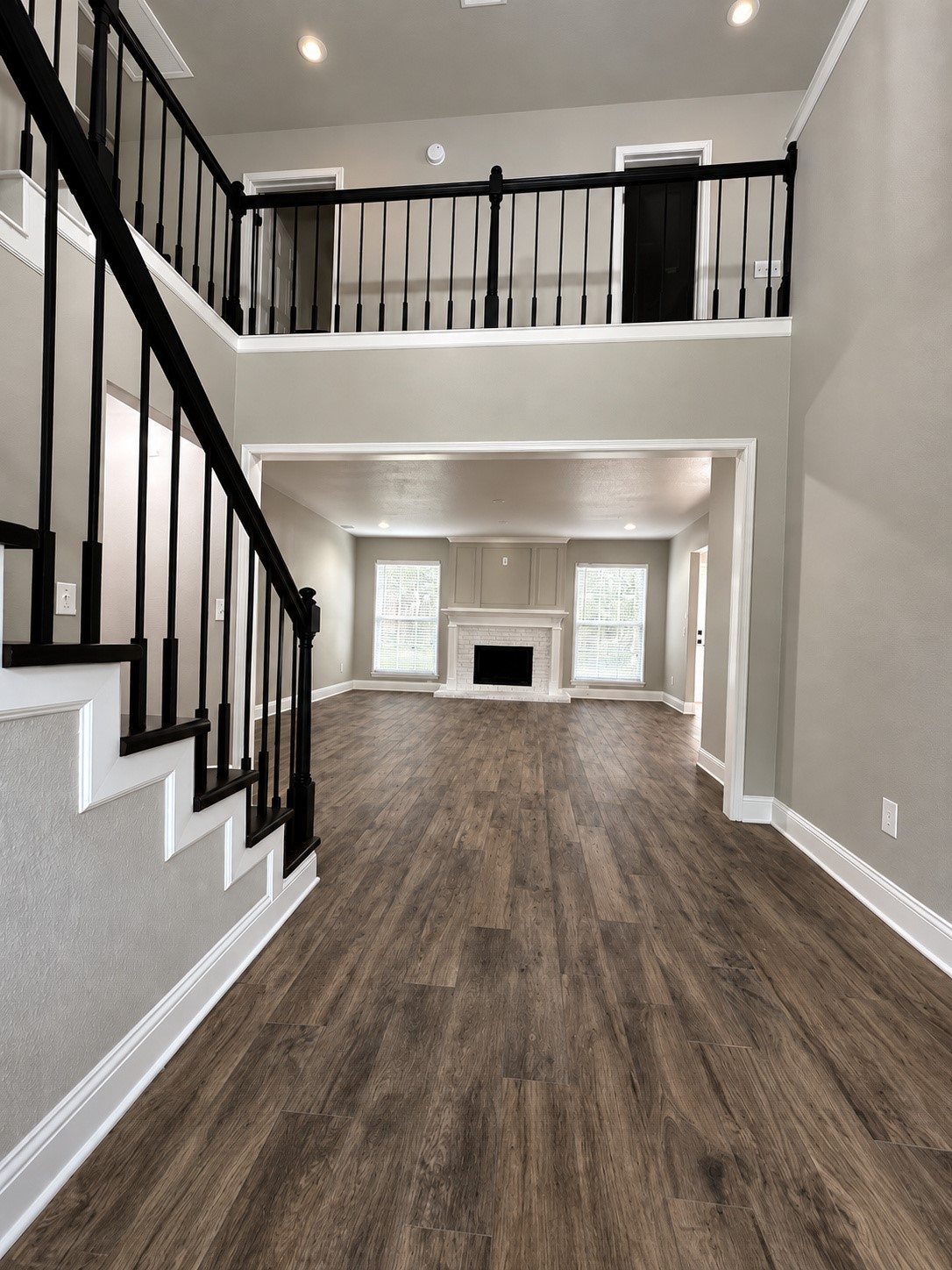 Grand two-story entry featuring beautiful wood-look flooring, soaring ceilings, and elegant black stair railings.