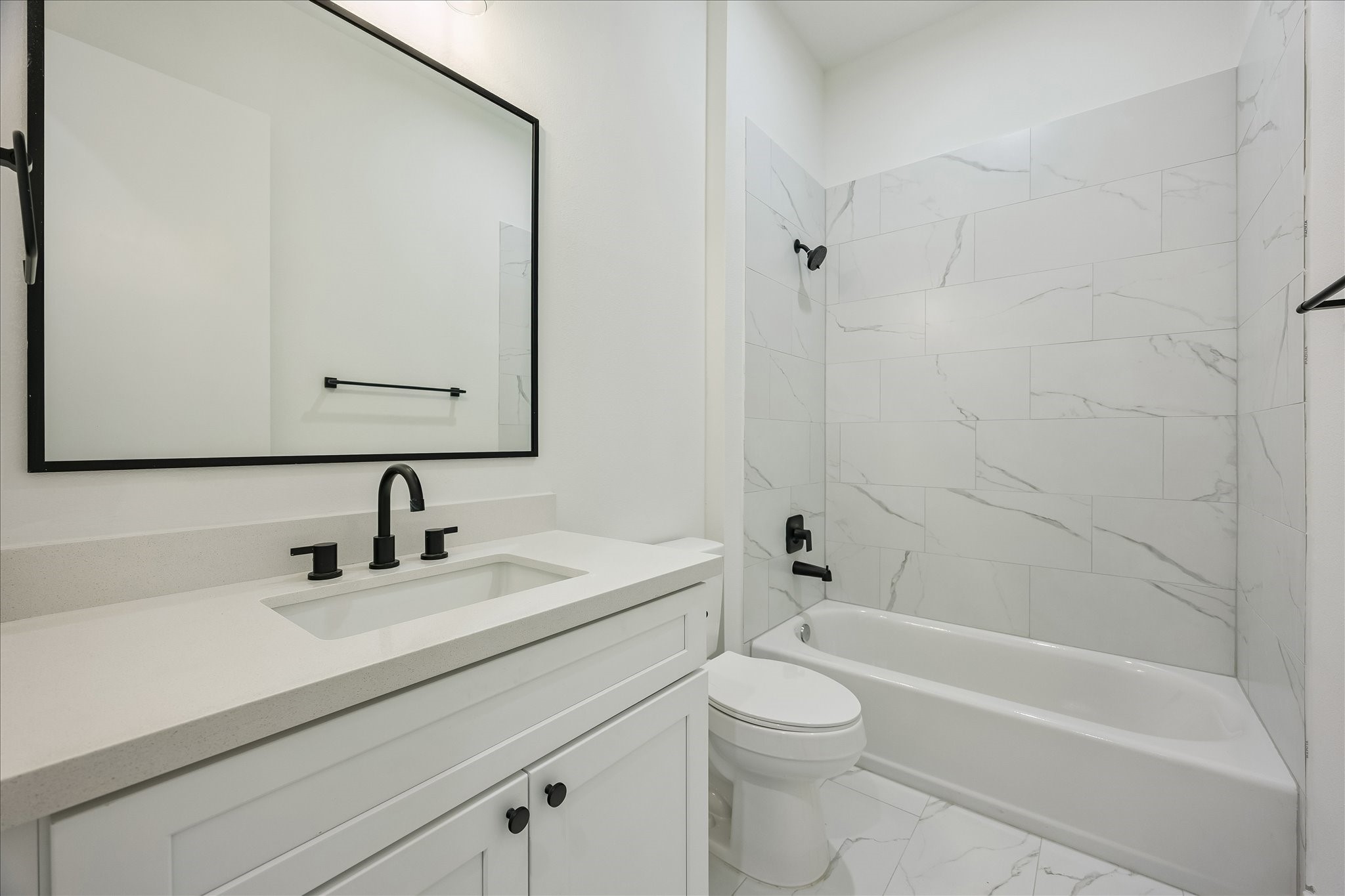 The secondary bedroom's ensuite bath is equally well appointed, featuring quartz countertops, designer tile, and a tub/shower combination.