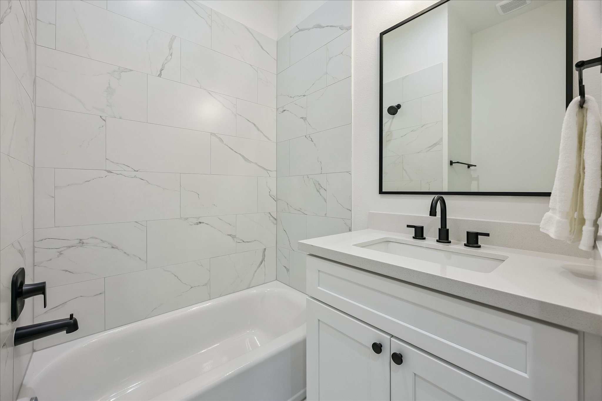 The ensuite first-floor bath showcases stylish tile, quartz countertops, and a tub/shower combination. The ensuite first-floor bath showcases stylish tile, quartz countertops, and a tub/shower combination.