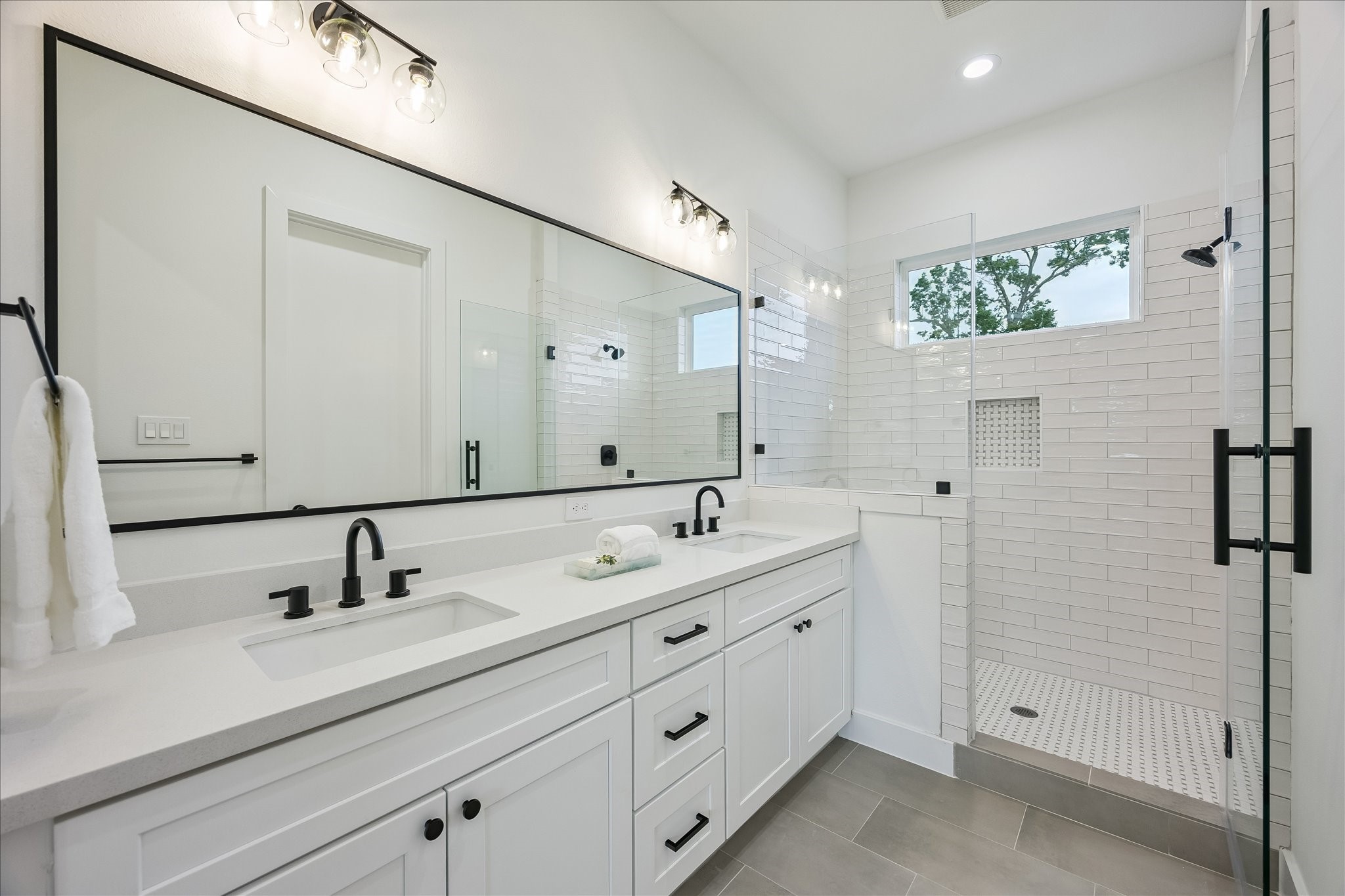 The spa-inspired primary bath features dual vanities and a spacious walk-in shower with a built-in bench. Designer tilework and a convenient shampoo niche add the perfect finishing touches.