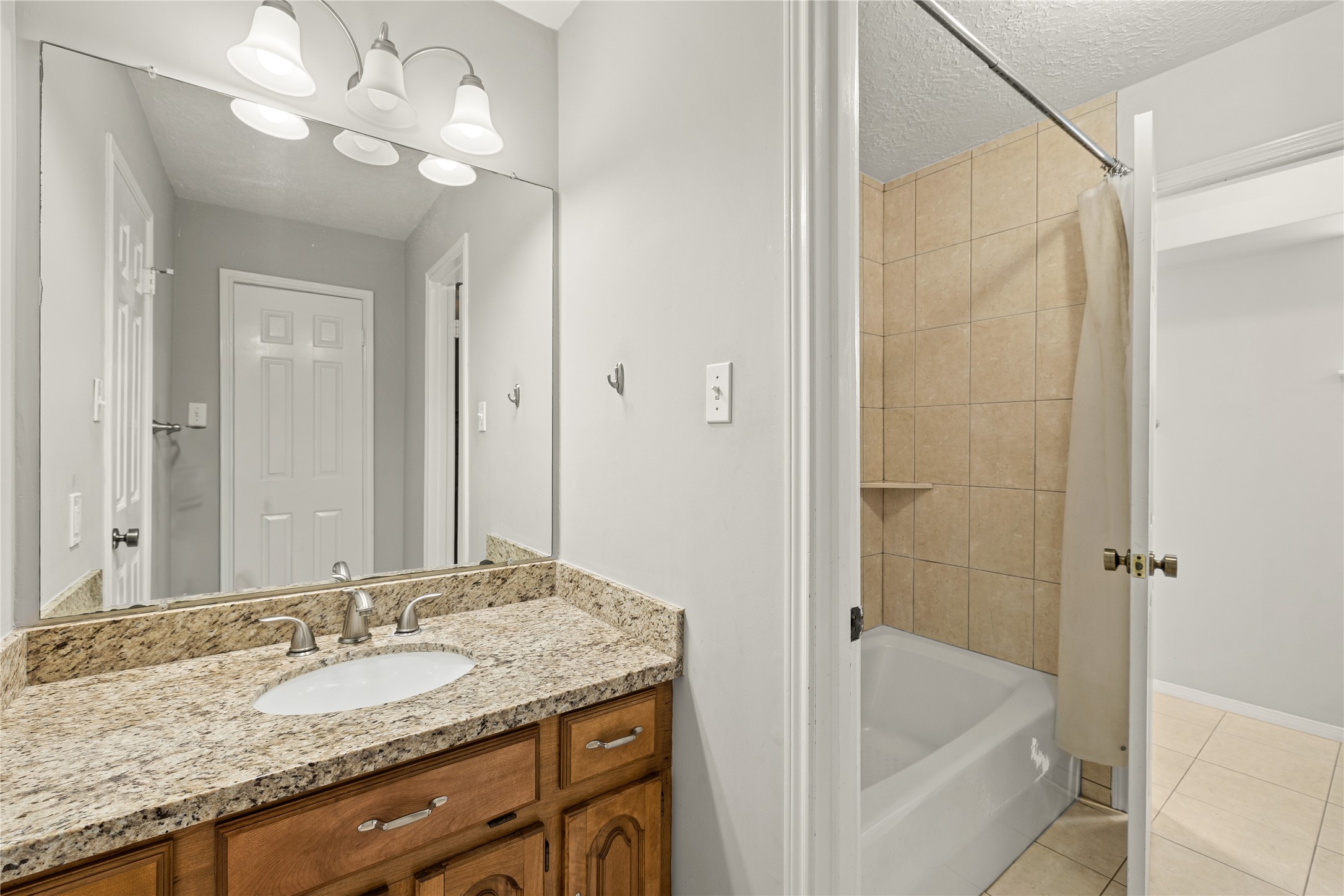 Secondary bathroom features a tub/shower combination with tile surround and tile flooring.