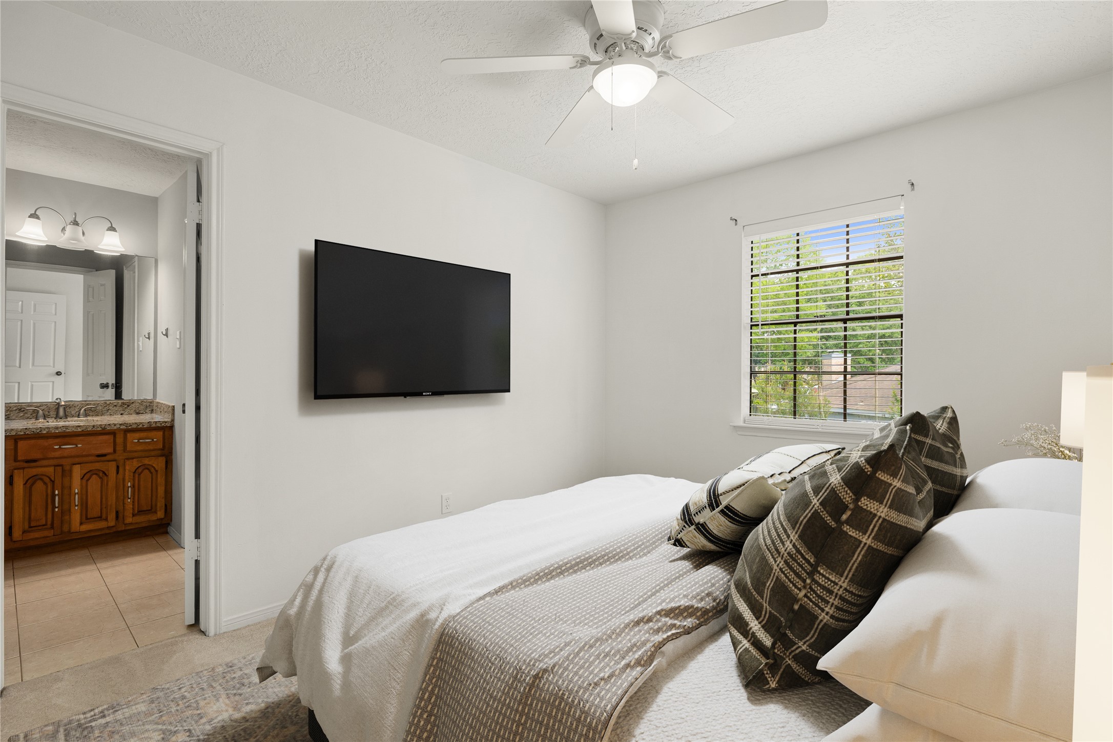 Spacious secondary bedroom featuring high ceilings, ceiling fan, plush carpet flooring, and private vanity area into shared secondary bathroom. *Virtually Staged