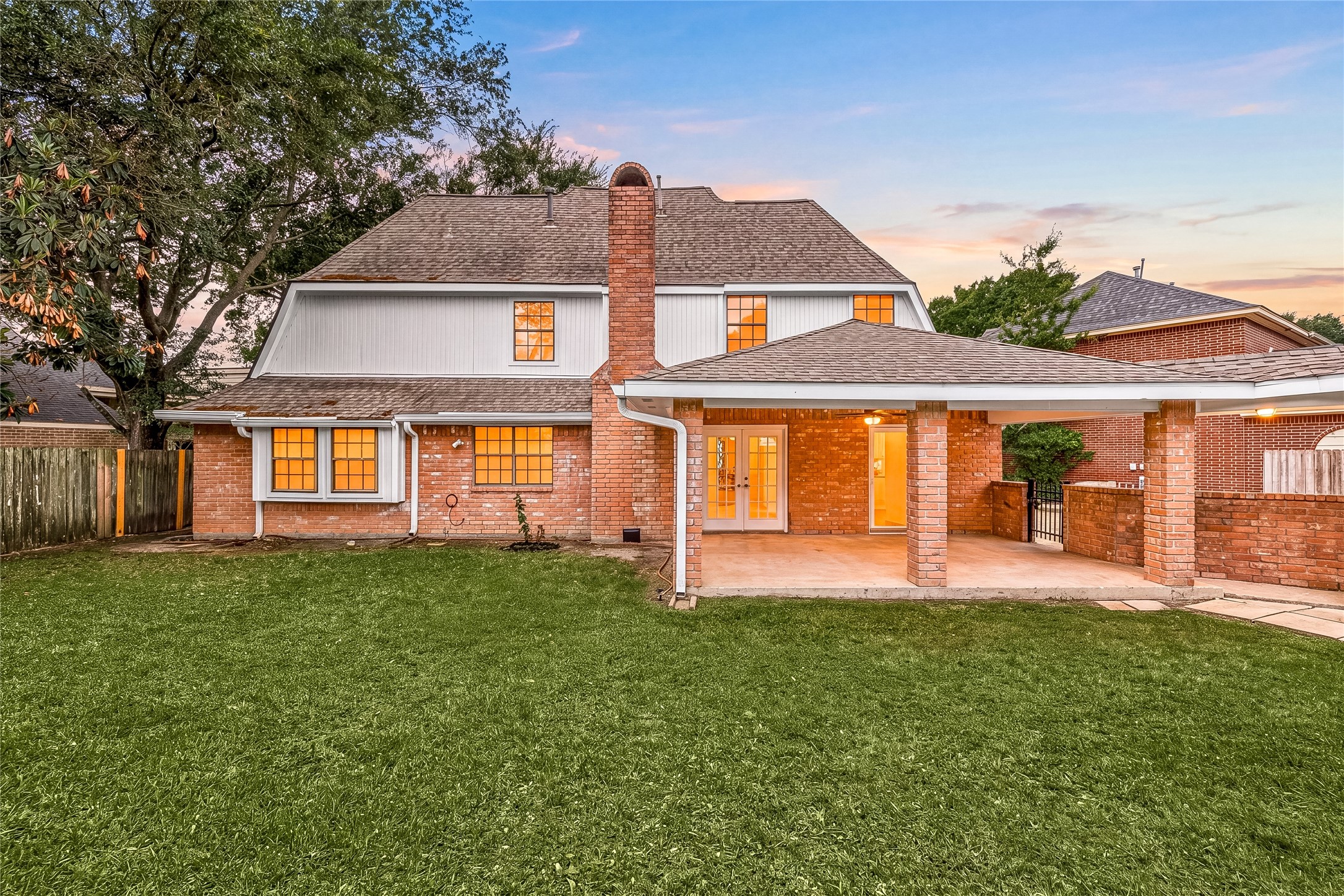 Step into your own private backyard oasis! This expansive, lush green lawn is perfect for play, gardening, or future poolside dreams. The classic brick exterior is accented by large windows that flood the home with natural light and overlook the peaceful outdoor space. Featuring mature trees for shade and a covered patio area, this backyard is the ultimate setting for summer BBQs and quiet evenings under the stars.